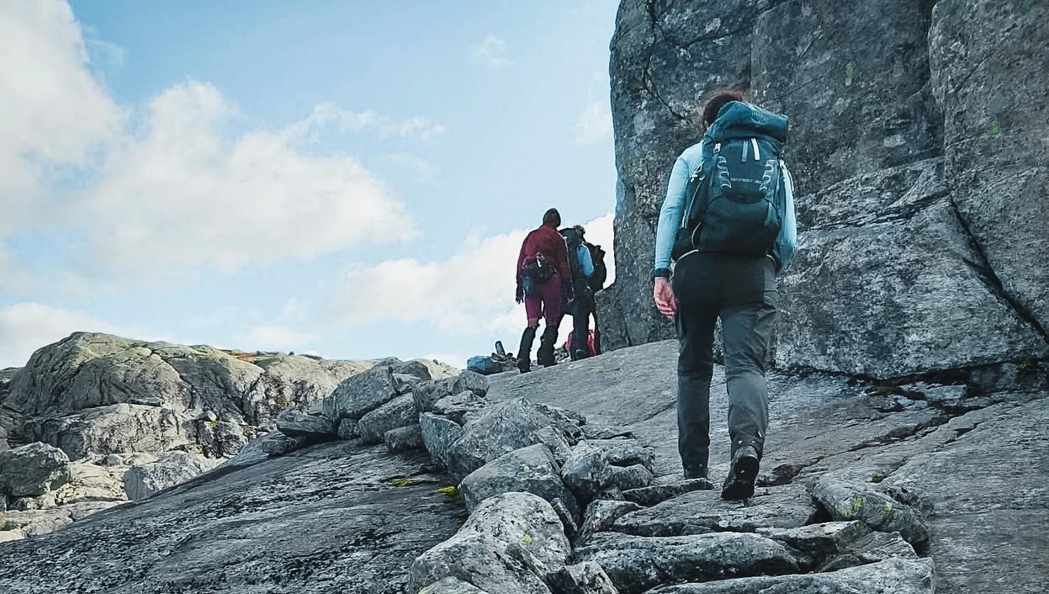 Mountain hikers crossing bare rock terrain in Hardanger, Norway, surrounded by open landscapes