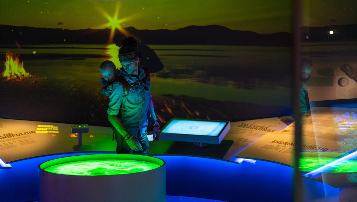Immerse yourself in interactive exhibits that blend education with wonder! A parent and child discover engaging displays, illuminated by neon colors and captivating visuals, perfect for family adventures.