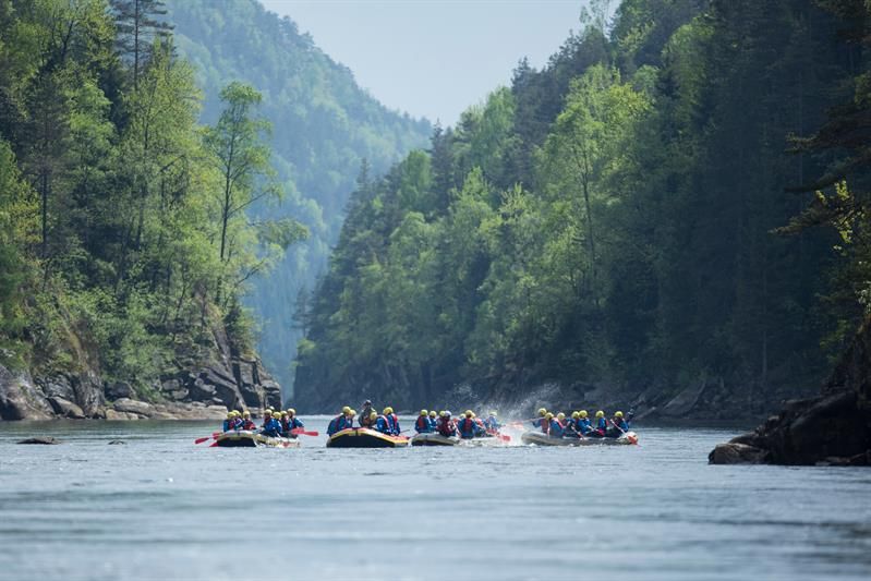 Vier Gruppen mit Raftingbooten, die im Wasser spielen.
