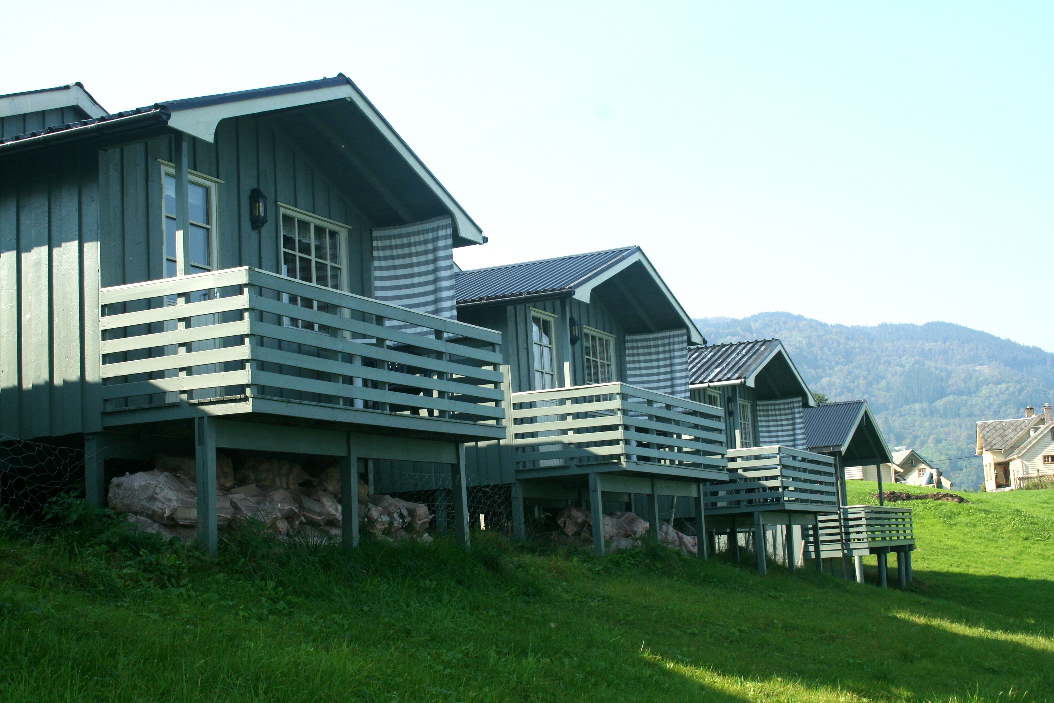 Traditional cabins with verandas overlooking the mountains and fjord at Oddland Camping in Hardanger.