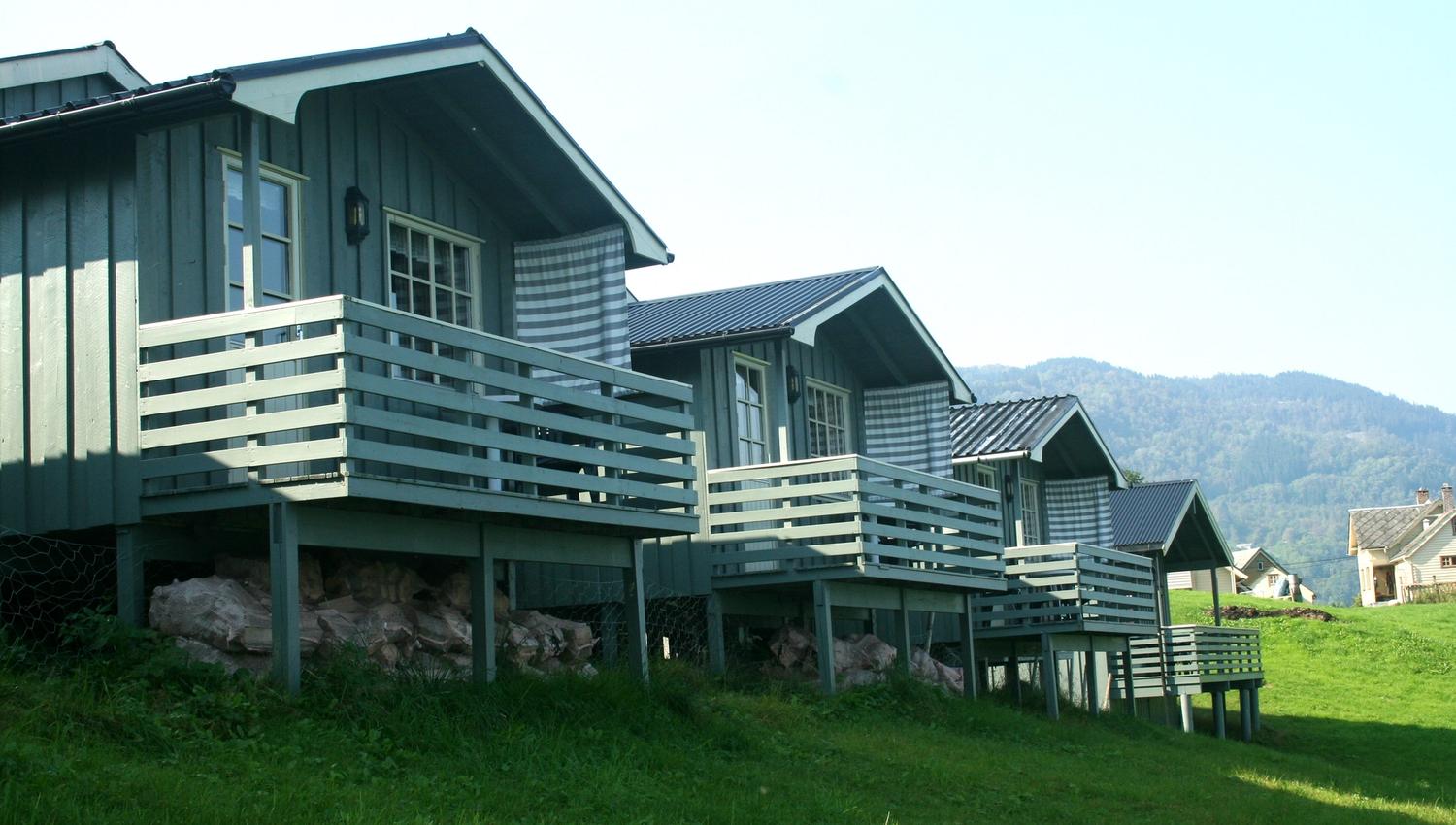 Traditional cabins with verandas overlooking the mountains and fjord at Oddland Camping in Hardanger.