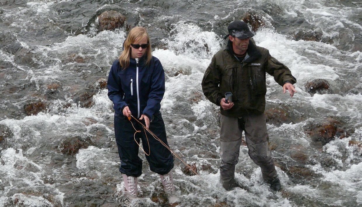 A man and a girl fishing in a river.