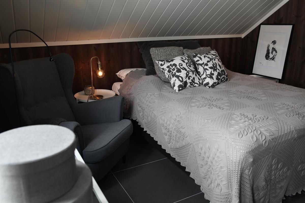  A bedroom with a bed, chairs, and soft lighting.