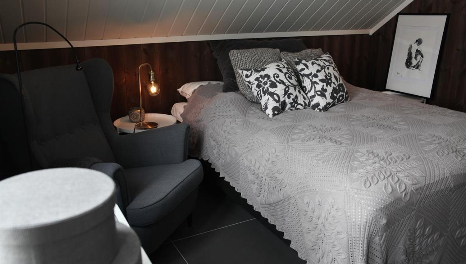 A bedroom with a bed, chairs, and soft lighting.
