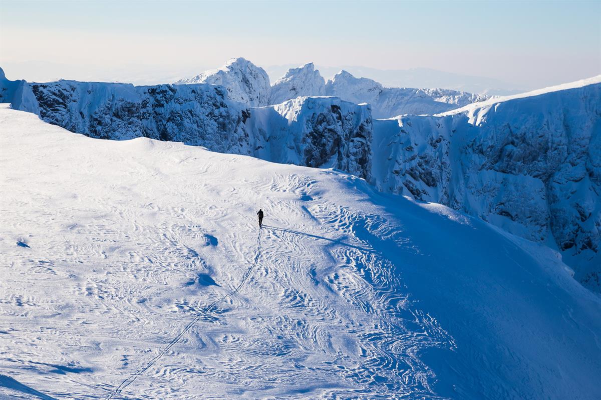 Bergskiläufer auf einem Plateau mit Abgründen und spitzen Gipfeln im Hintergrund