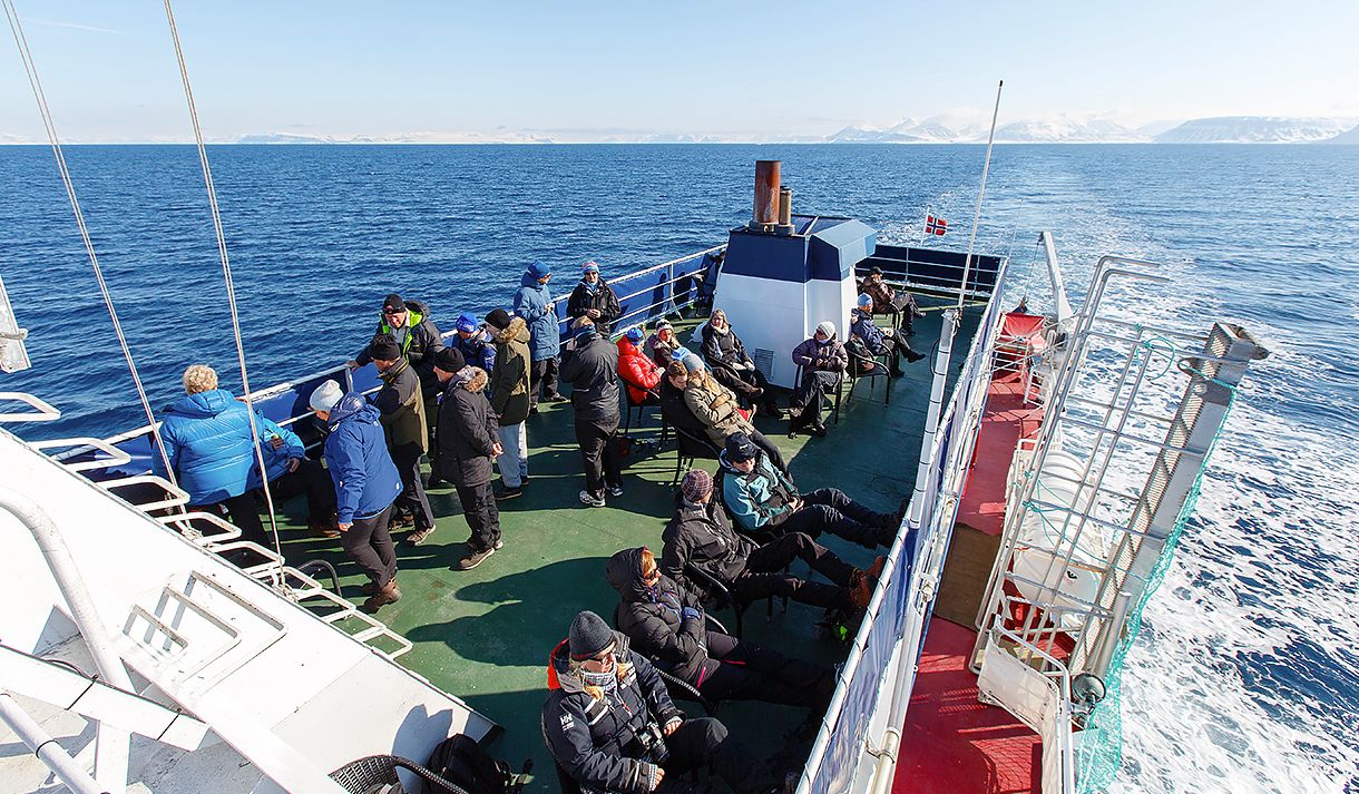 Gjester om bord en båt som ser ut over en fjord