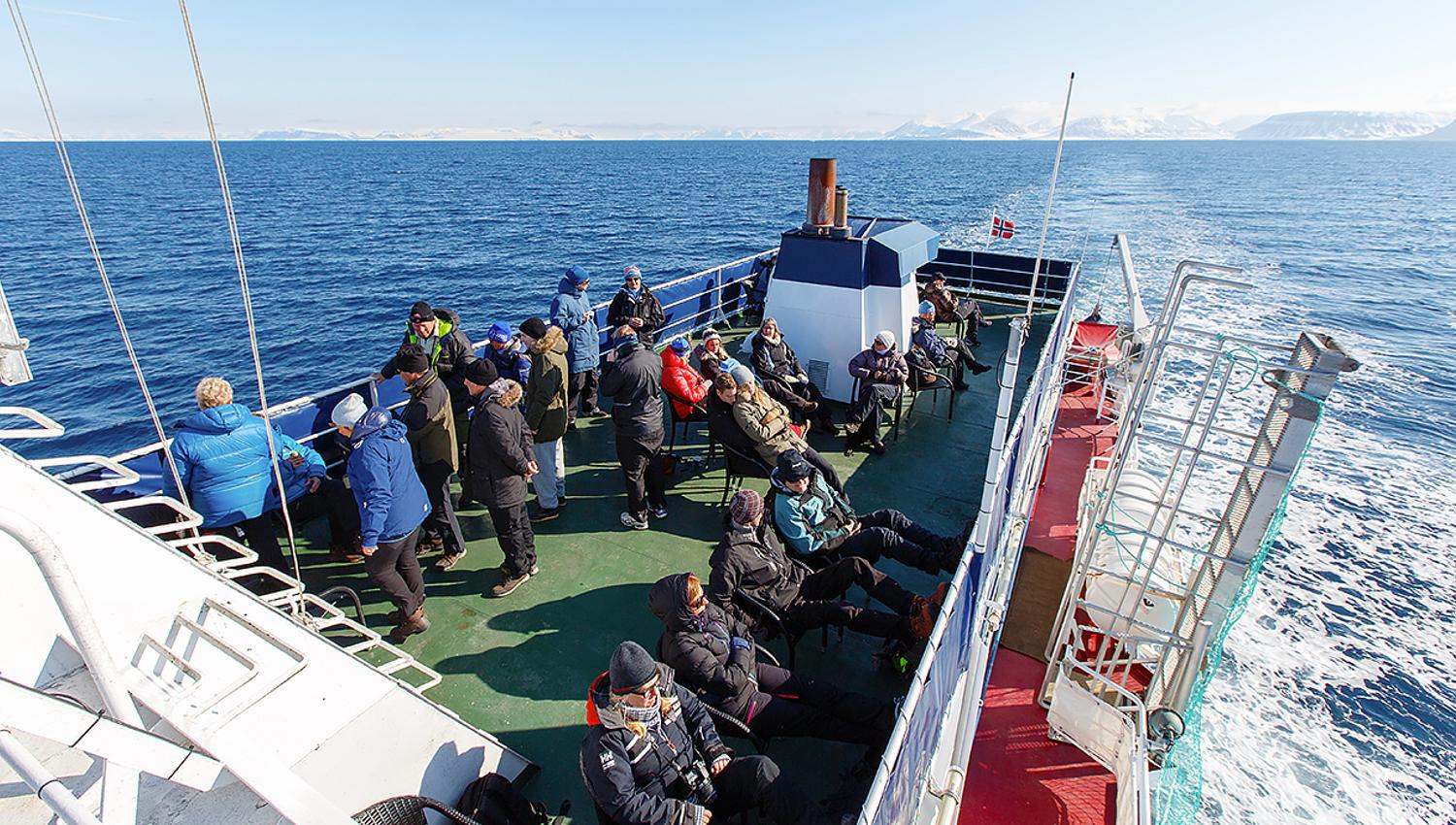 Gjester om bord en båt som ser ut over en fjord