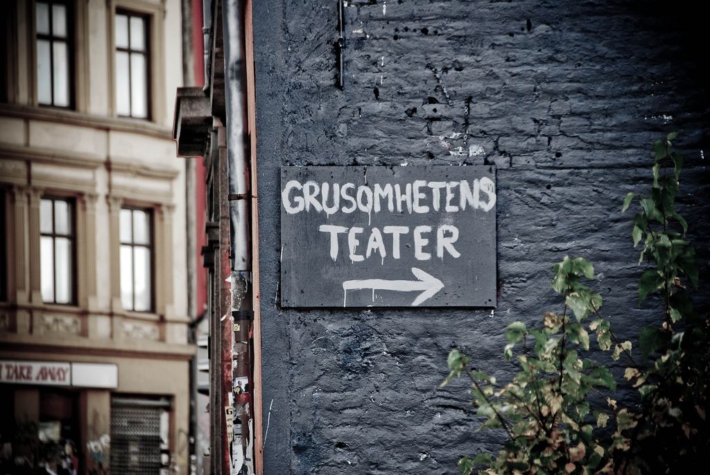 Black brick wall with a sign toward Theatre of Cruelty.