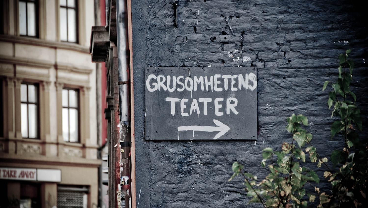Black brick wall with a sign toward Theatre of Cruelty.
