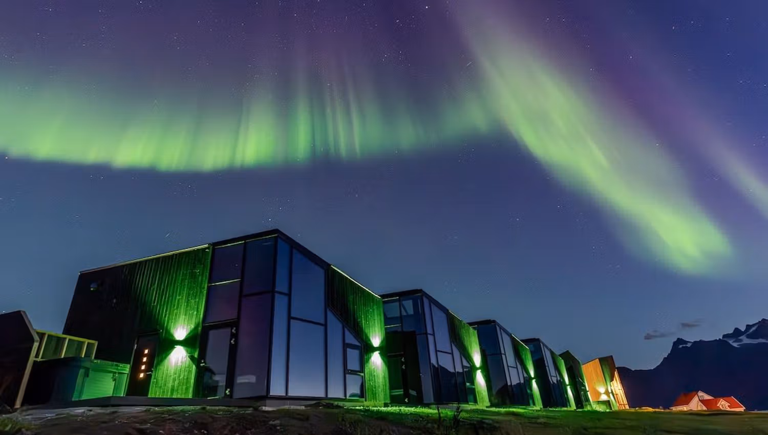 A photo of the hotel Lyngen North, located in the Tromsø region of Northern Norway. It is under spectacular Northern Lights.
