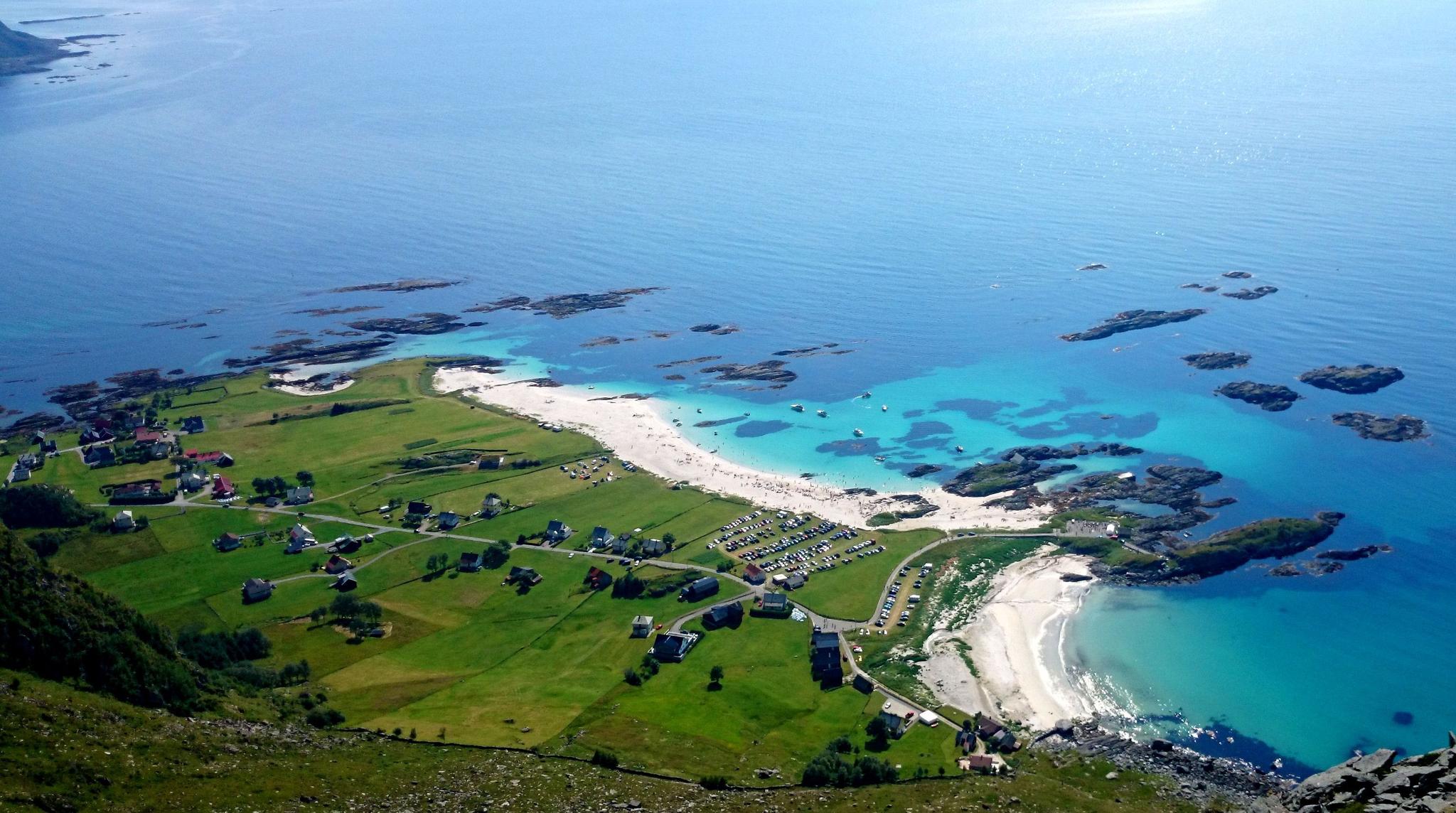 Grotlesanden. Aerial view of a green coastal village with roads and houses beside white-sand beaches and turquoise water with rocky islets..