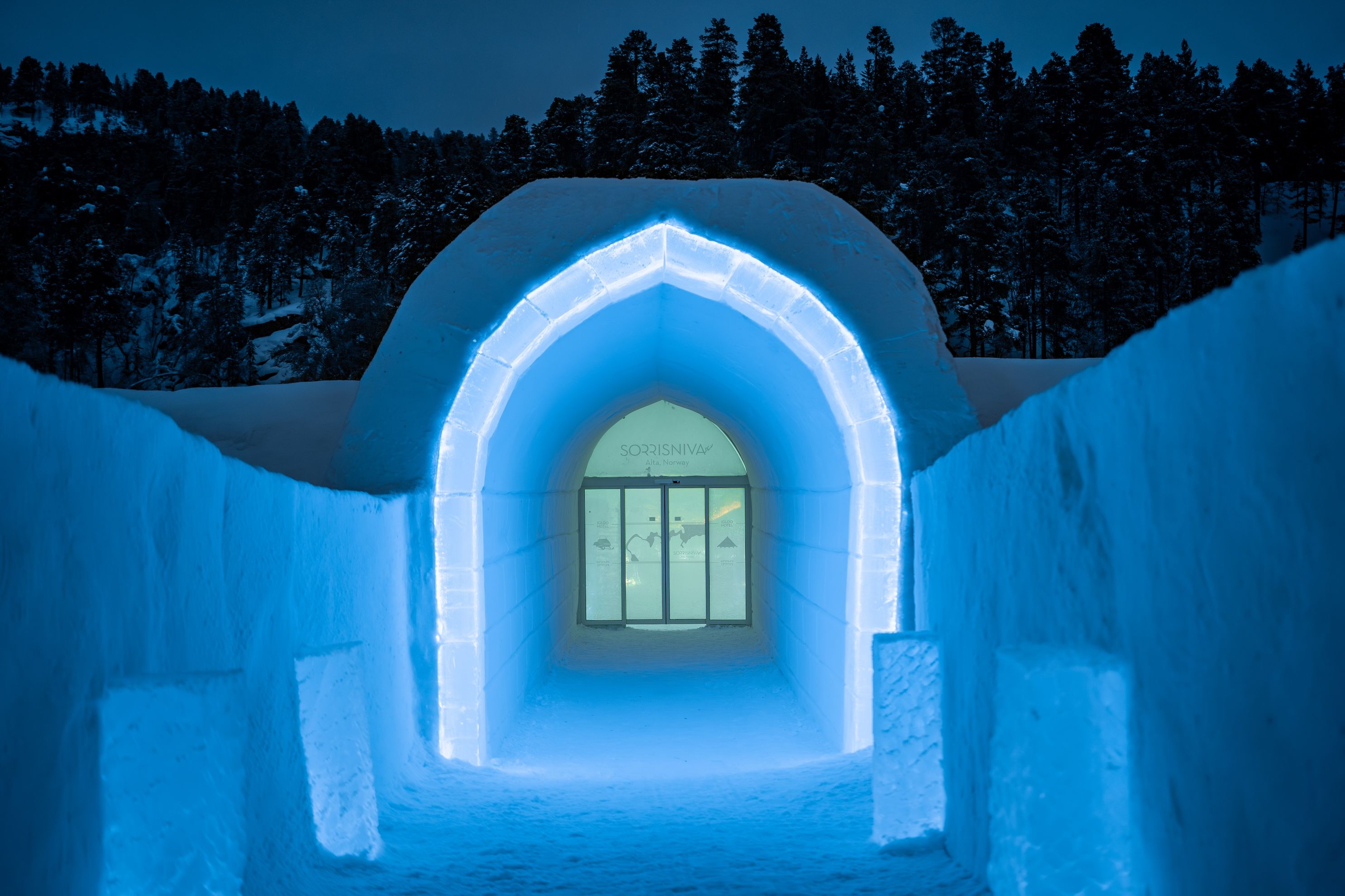 Verken de magische sneeuwgang van Sorrisniva in Noorwegen. De betoverende blauwe verlichting en de majestueuze boog creëren een unieke sfeer, perfect voor een winterse ontdekkingstocht.