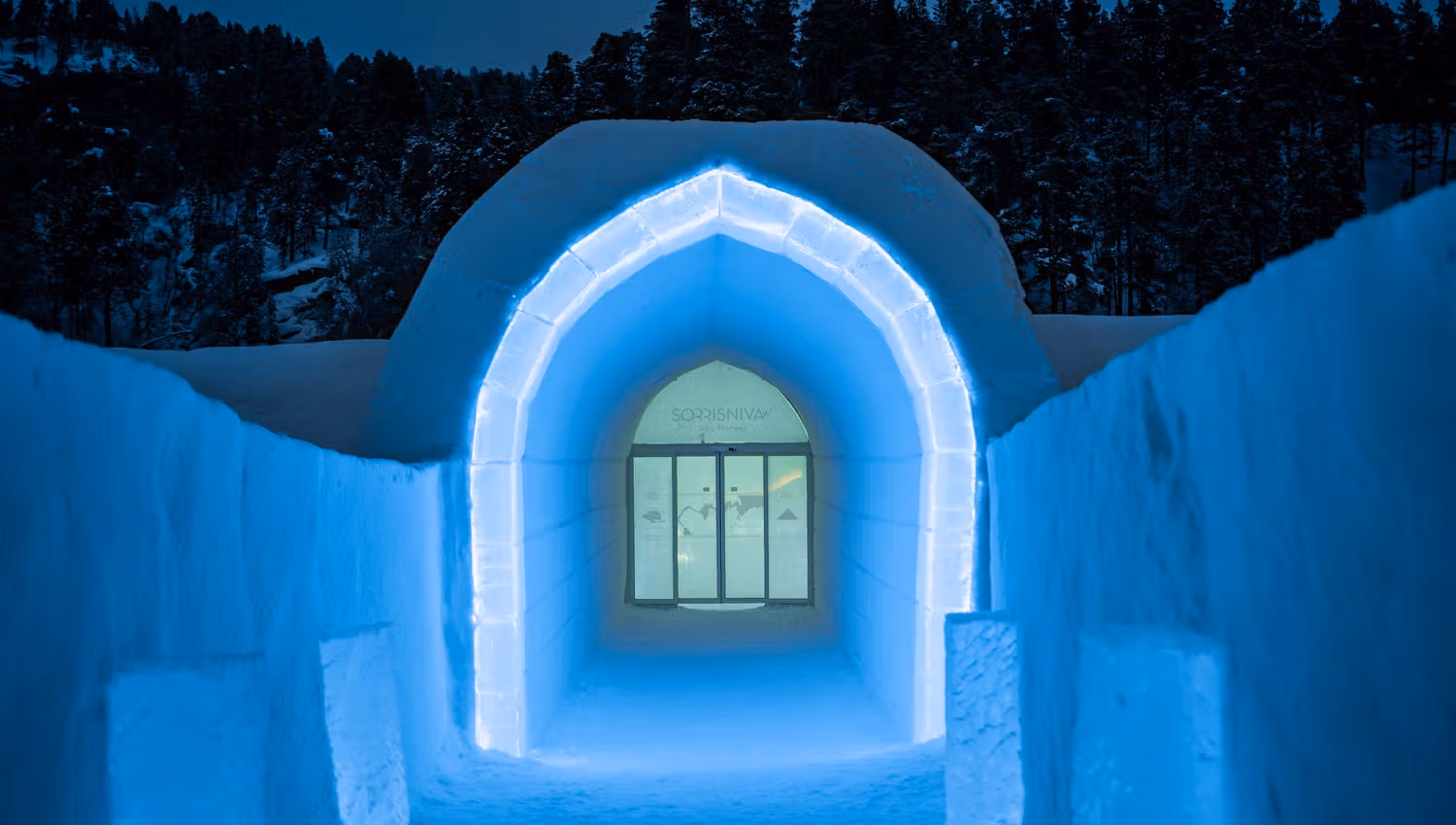 Verken de magische sneeuwgang van Sorrisniva in Noorwegen. De betoverende blauwe verlichting en de majestueuze boog creëren een unieke sfeer, perfect voor een winterse ontdekkingstocht.