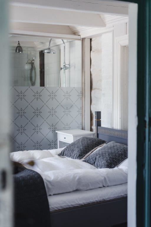 A traditionally furnished bedroom at Skrivergaarden with a double bed, classic details and a private bathroom.
