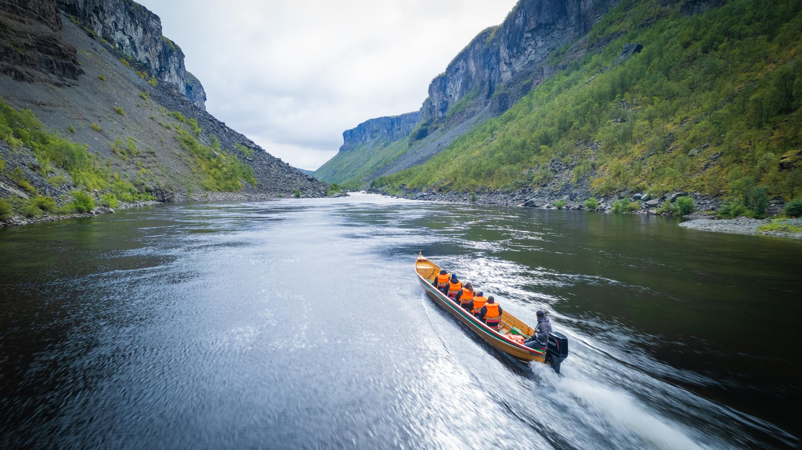 Un bateau navigue sur une rivière entourée de falaises verdoyantes.