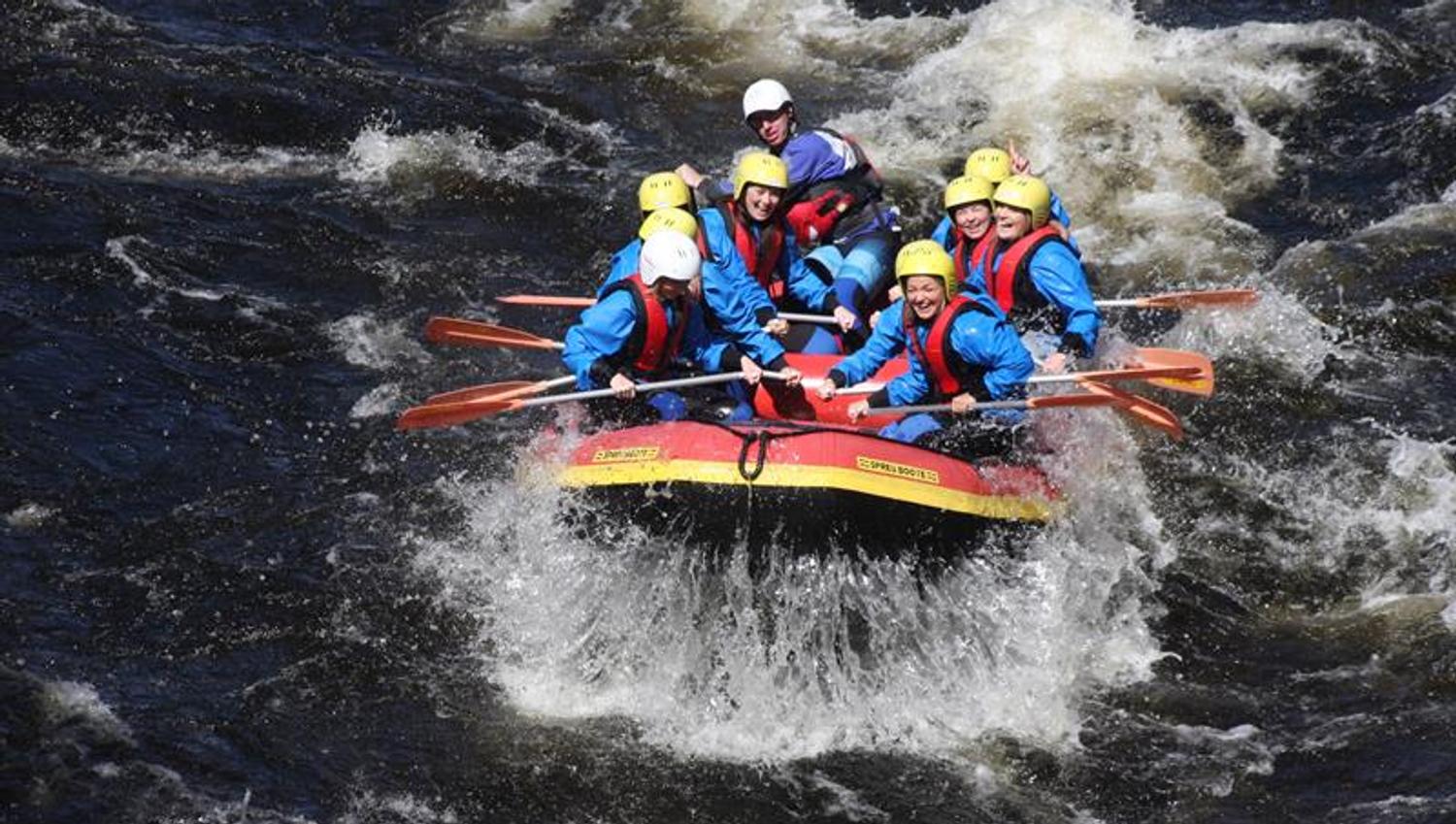 Rafting, mit Menschen in blauen Anzügen und gelben Helmen