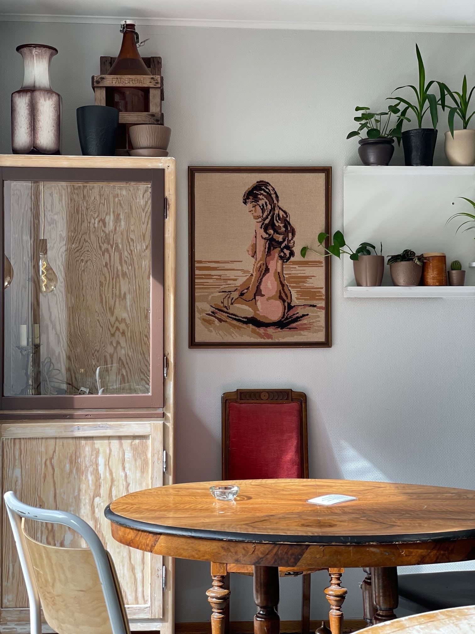 Hjørne med rundt trebord, kunst på veggen og dekorative hyller