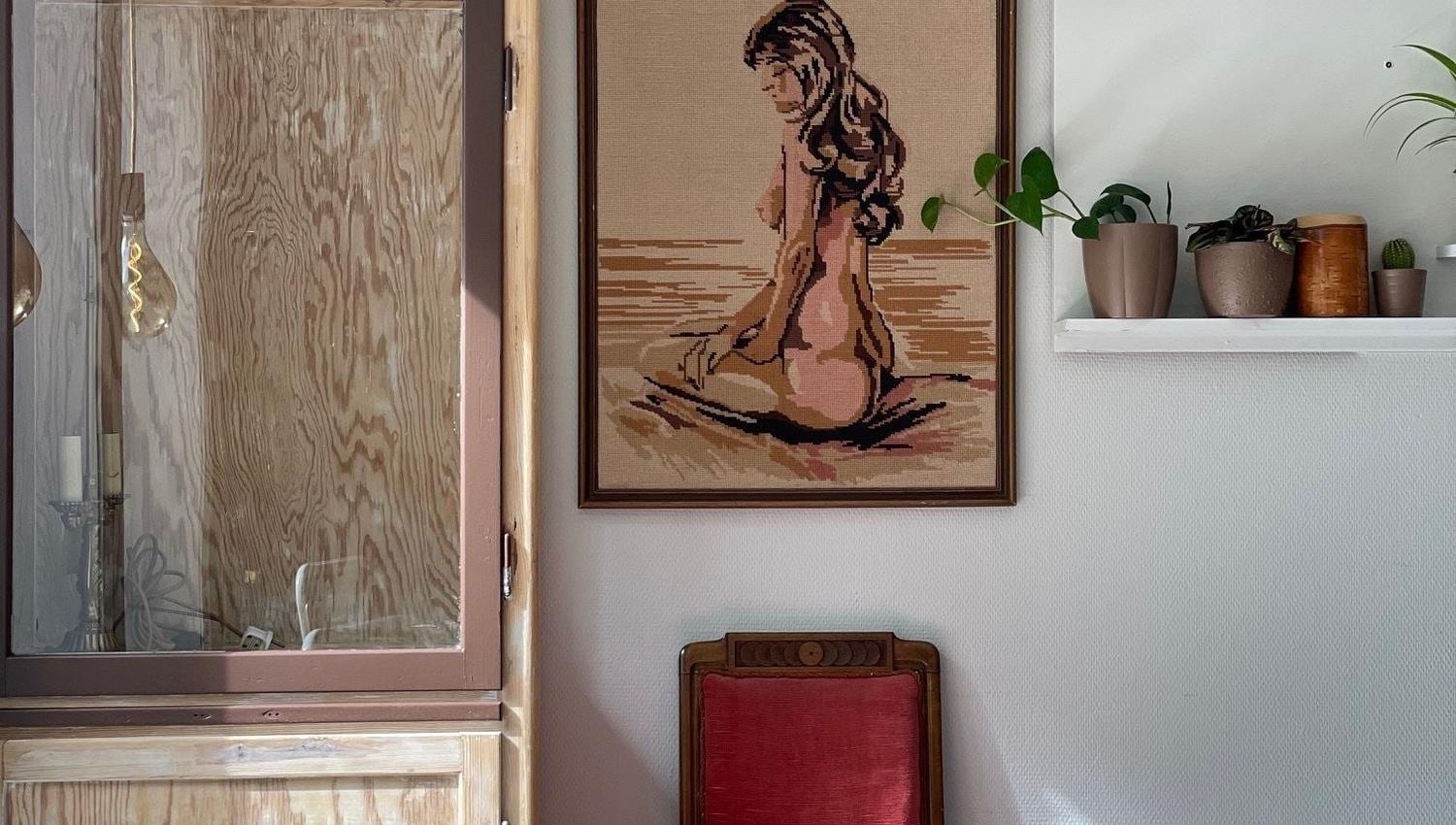 Hjørne med rundt trebord, kunst på veggen og dekorative hyller