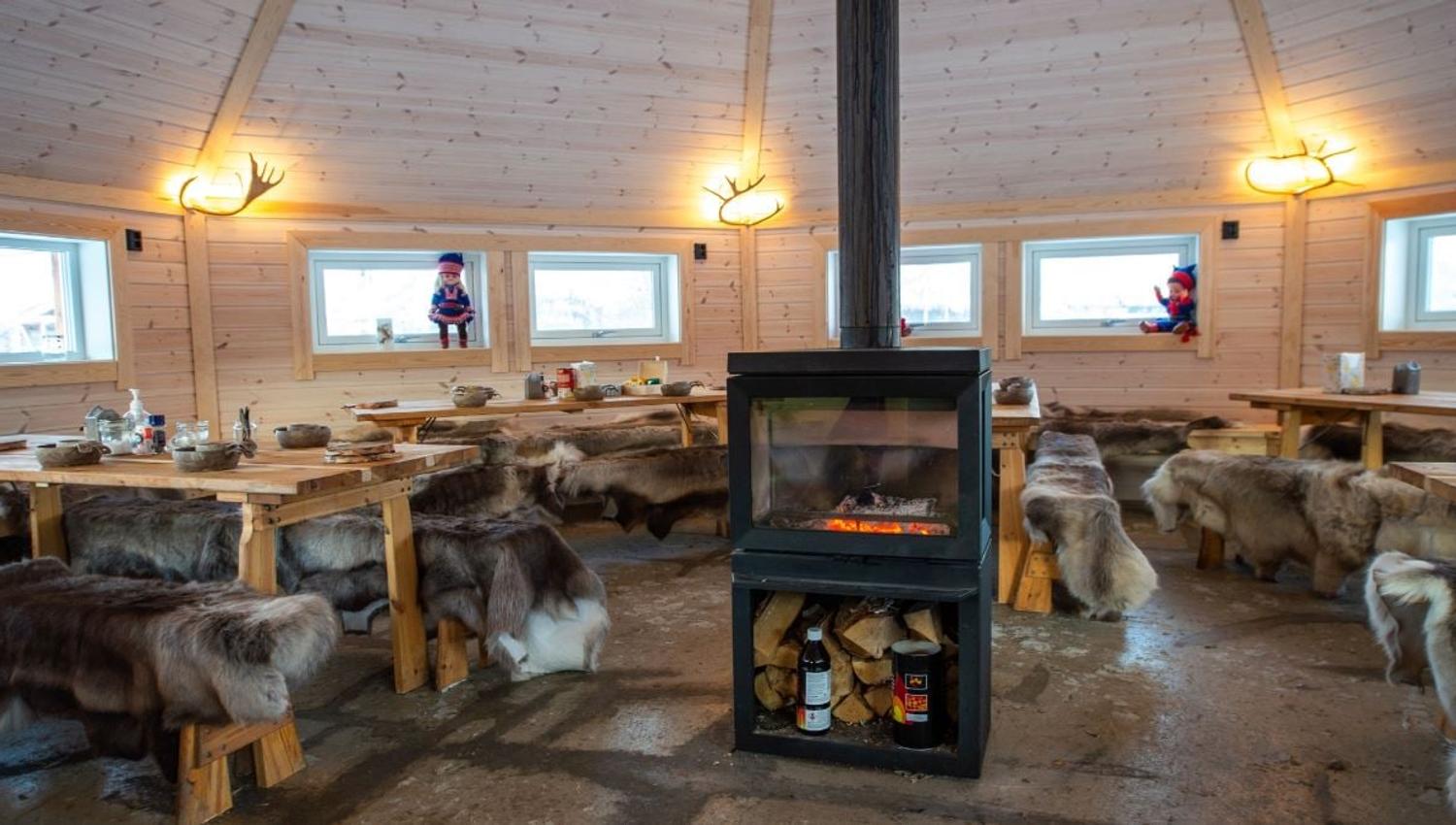 Interior of a traditional lavvu with a fireplace and seating during a Sámi cultural experience with Tromsø Lapland.