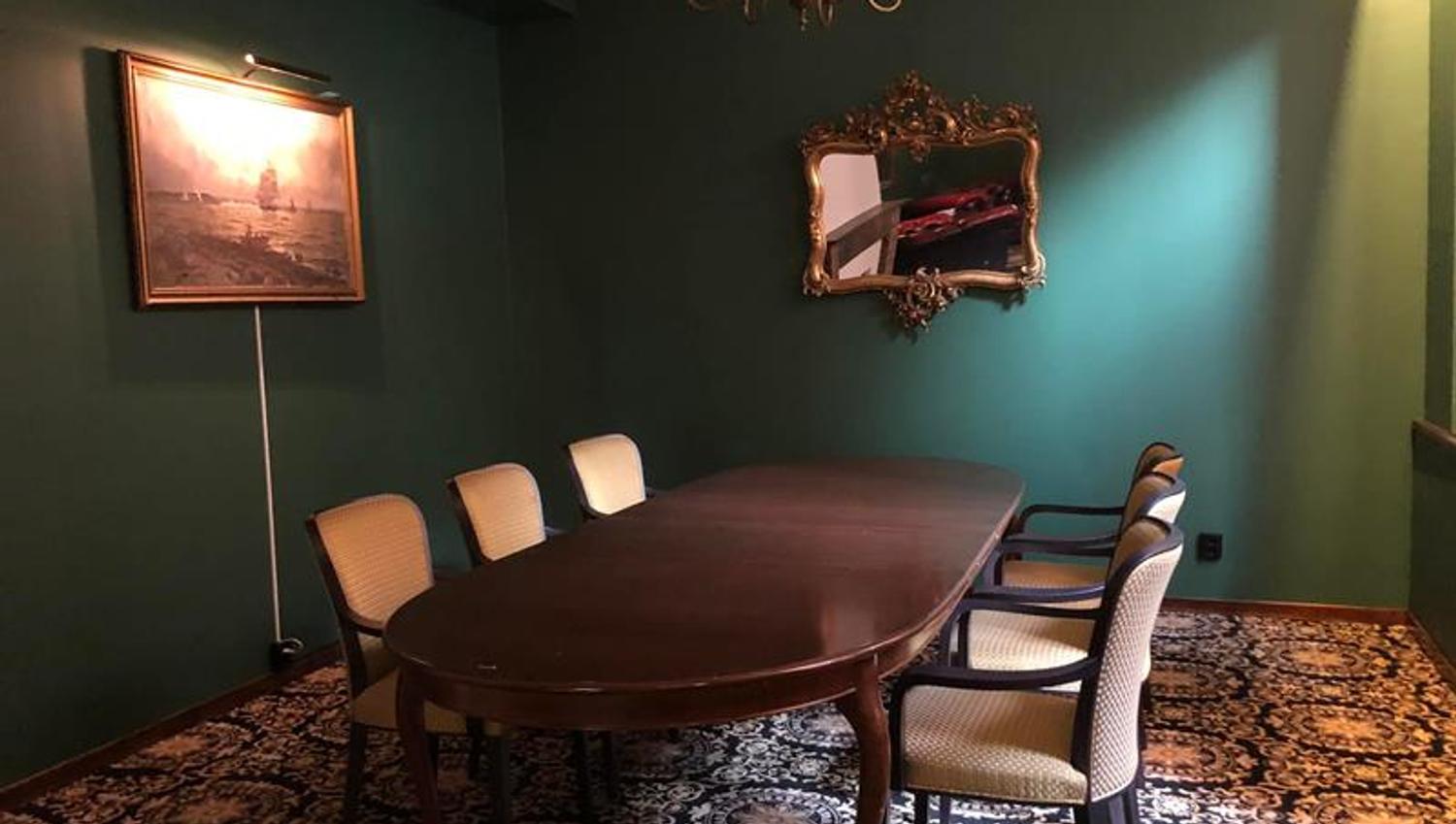 Møterom på Thon Hotel Høyers med grønne vegger, mønstrede vegg til vegg teppe og et ovalt bord med 6 stoler rundt. Speil og et maleri på vegen