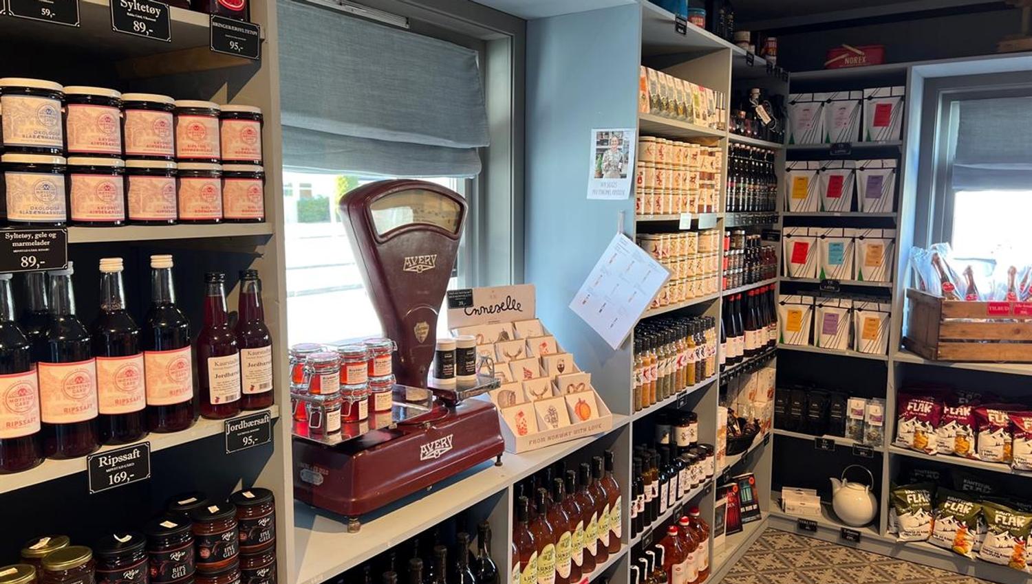 Shelves in a country store filled with a wide variety of foods and products, including jams and dry goods.
