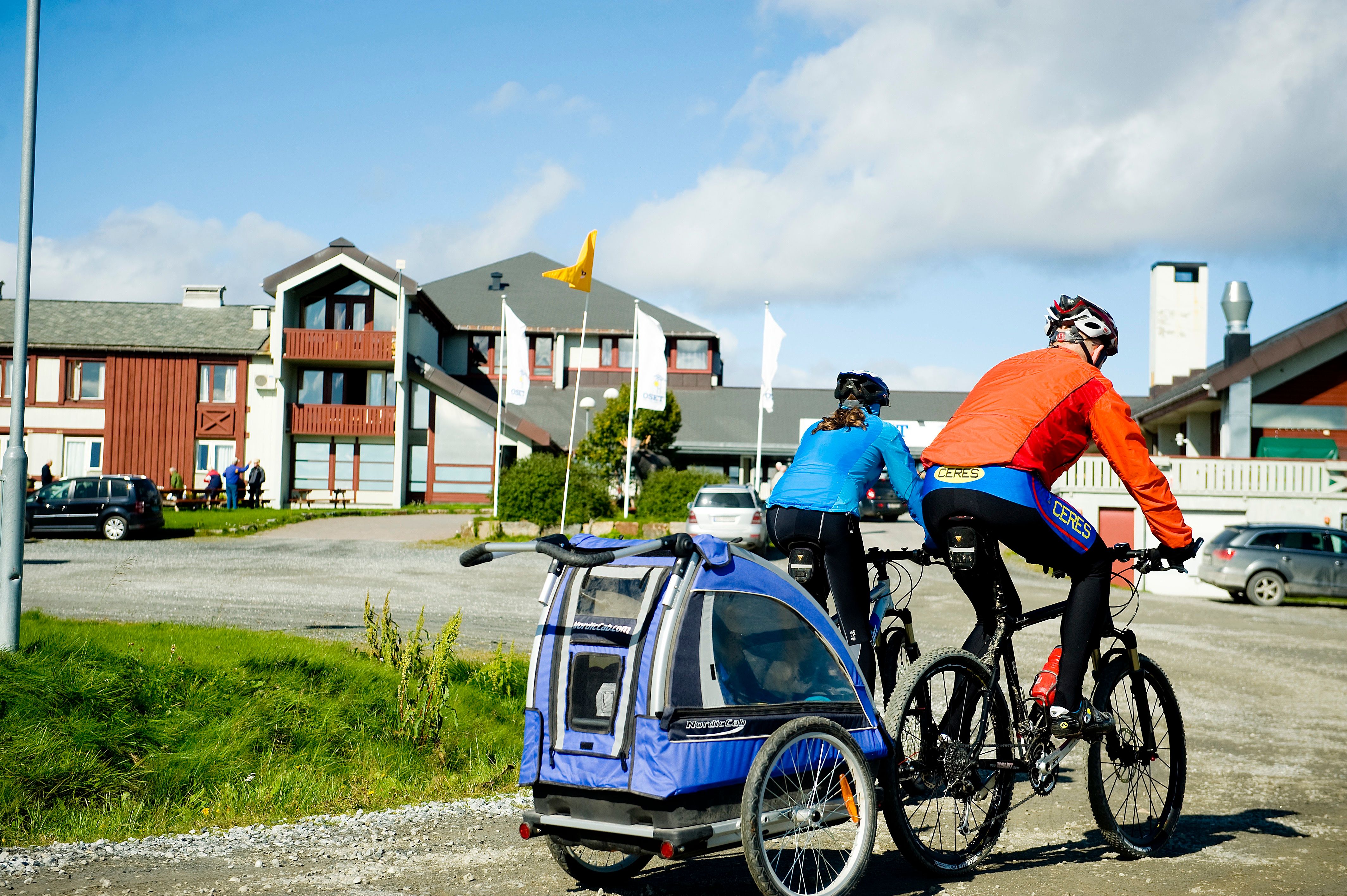 Syklister med sykkeltilhenger utenfor Oset Fjellhotell