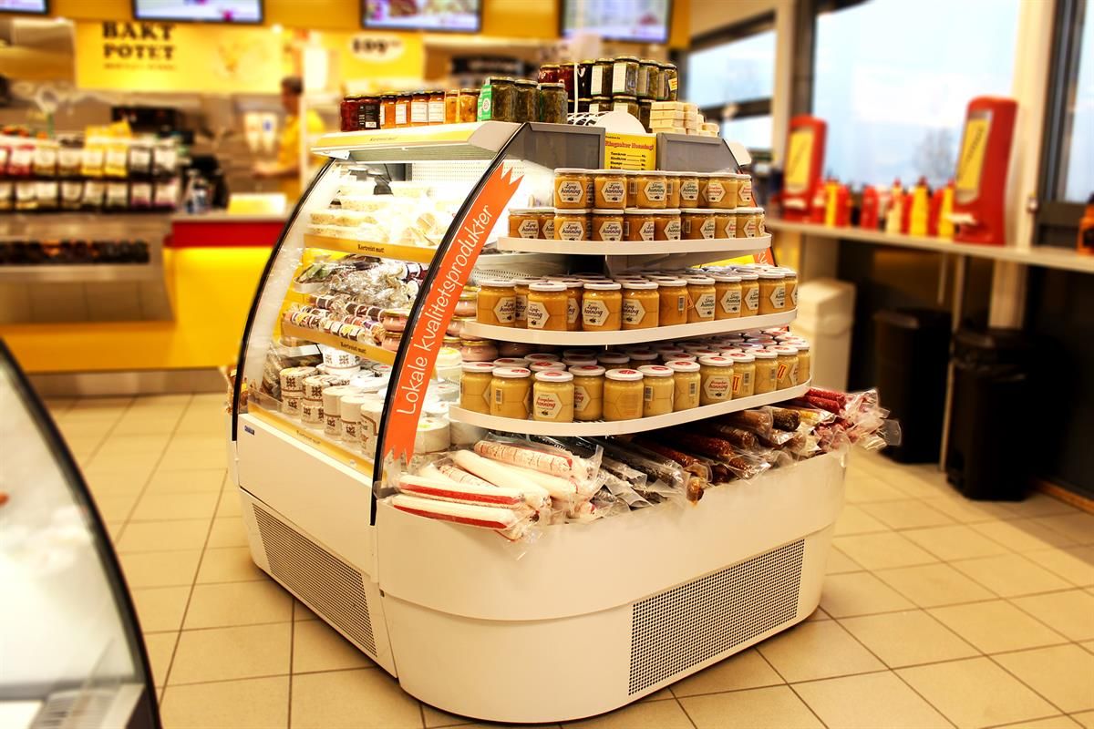 A round store display filled with pre-packaged baked goods and snacks, placed in a bright and modern retail area.