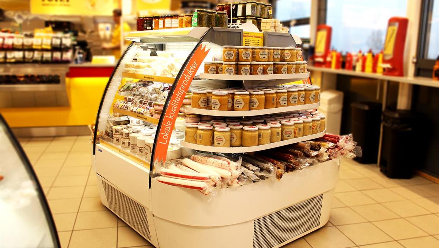 A round store display filled with pre-packaged baked goods and snacks, placed in a bright and modern retail area.