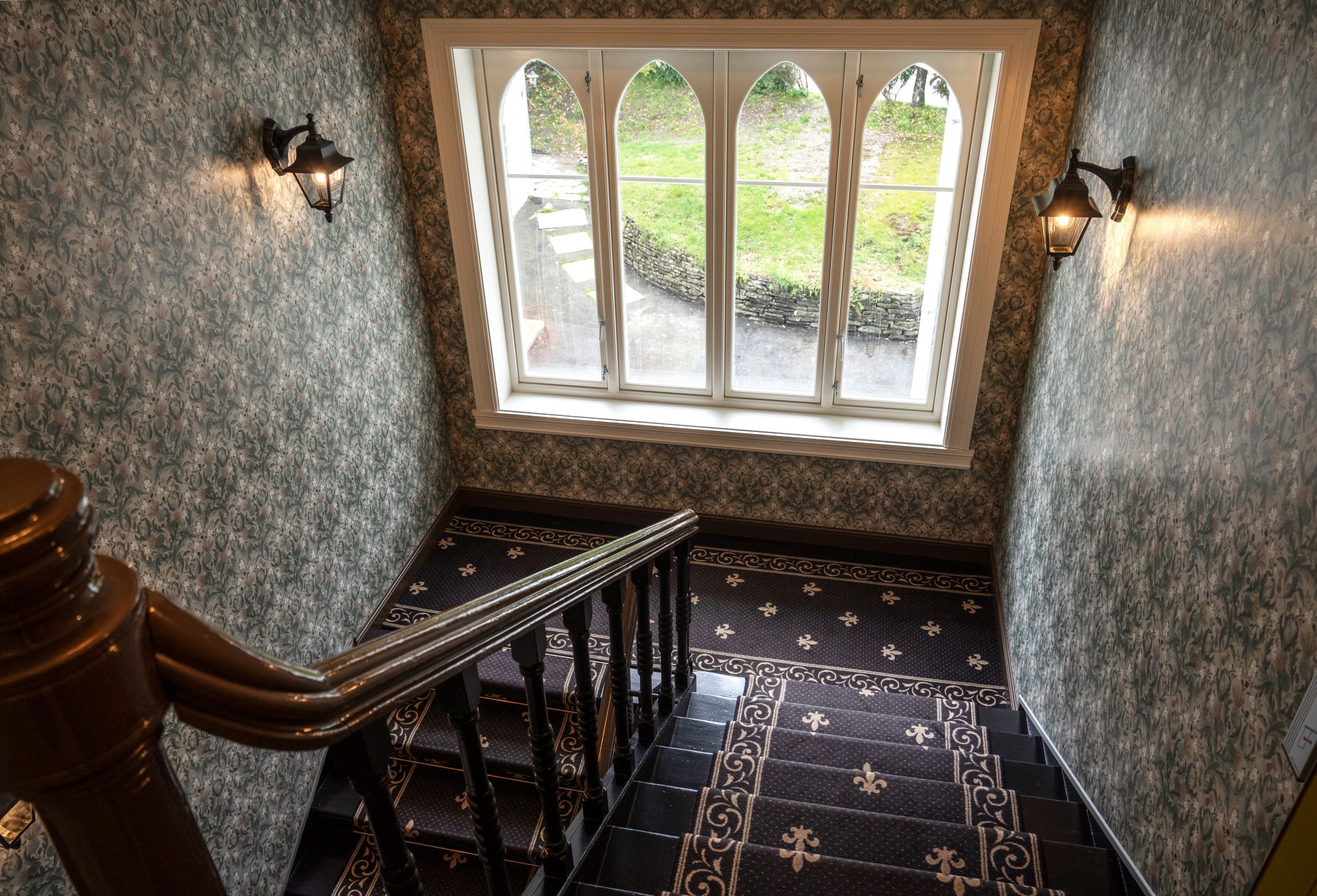 Charming historic staircase at Thon Hotel Sandven, featuring beautiful tiles and a view of the garden.