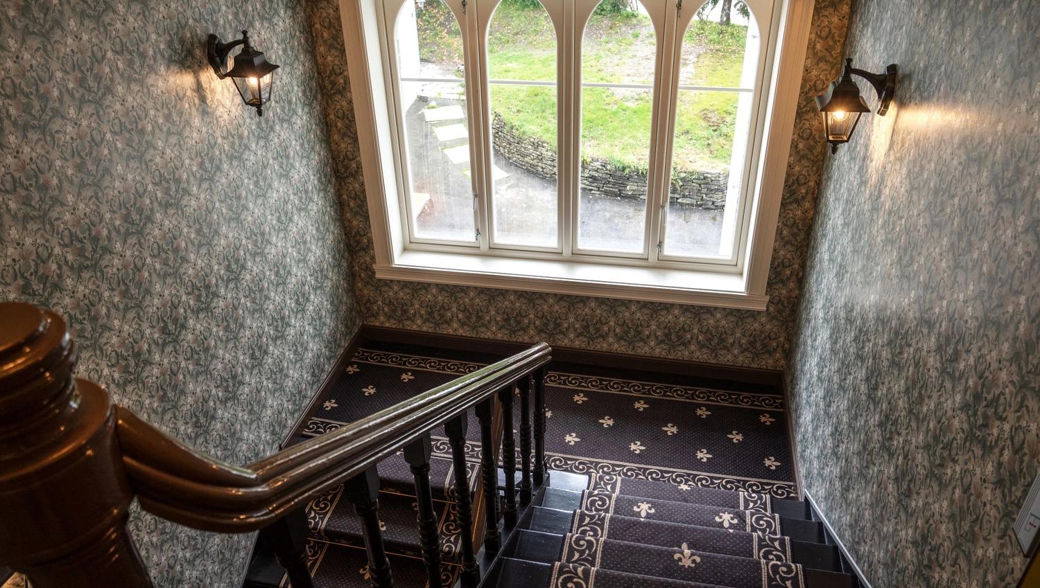 Charming historic staircase at Thon Hotel Sandven, featuring beautiful tiles and a view of the garden.