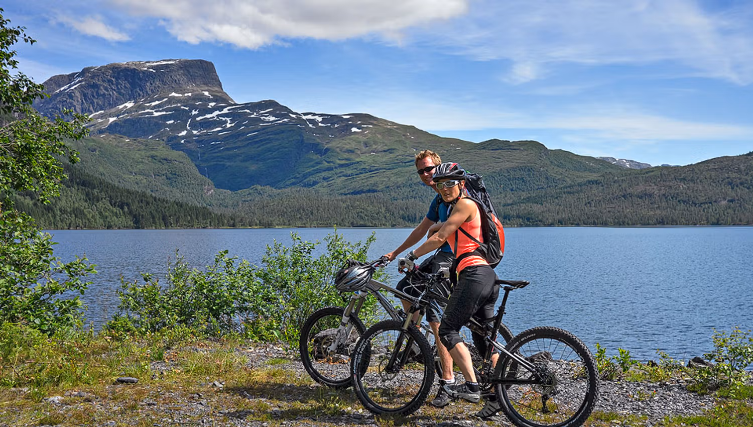 Two cyclists by Solsævatnet in Hardanger – a scenic biking experience surrounded by mountains and water.