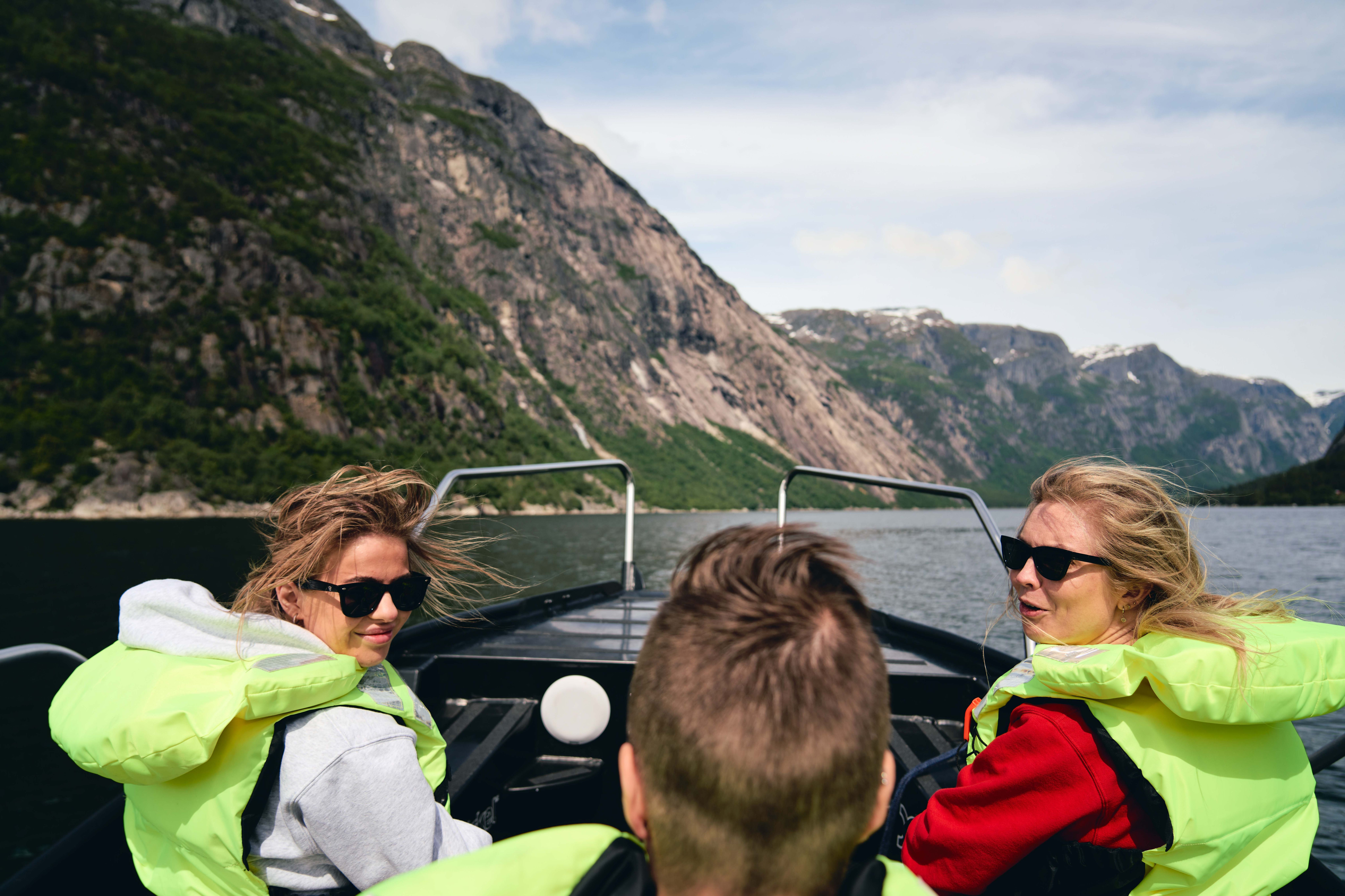Three passengers with wind in their hair  laughing onboard the boat.