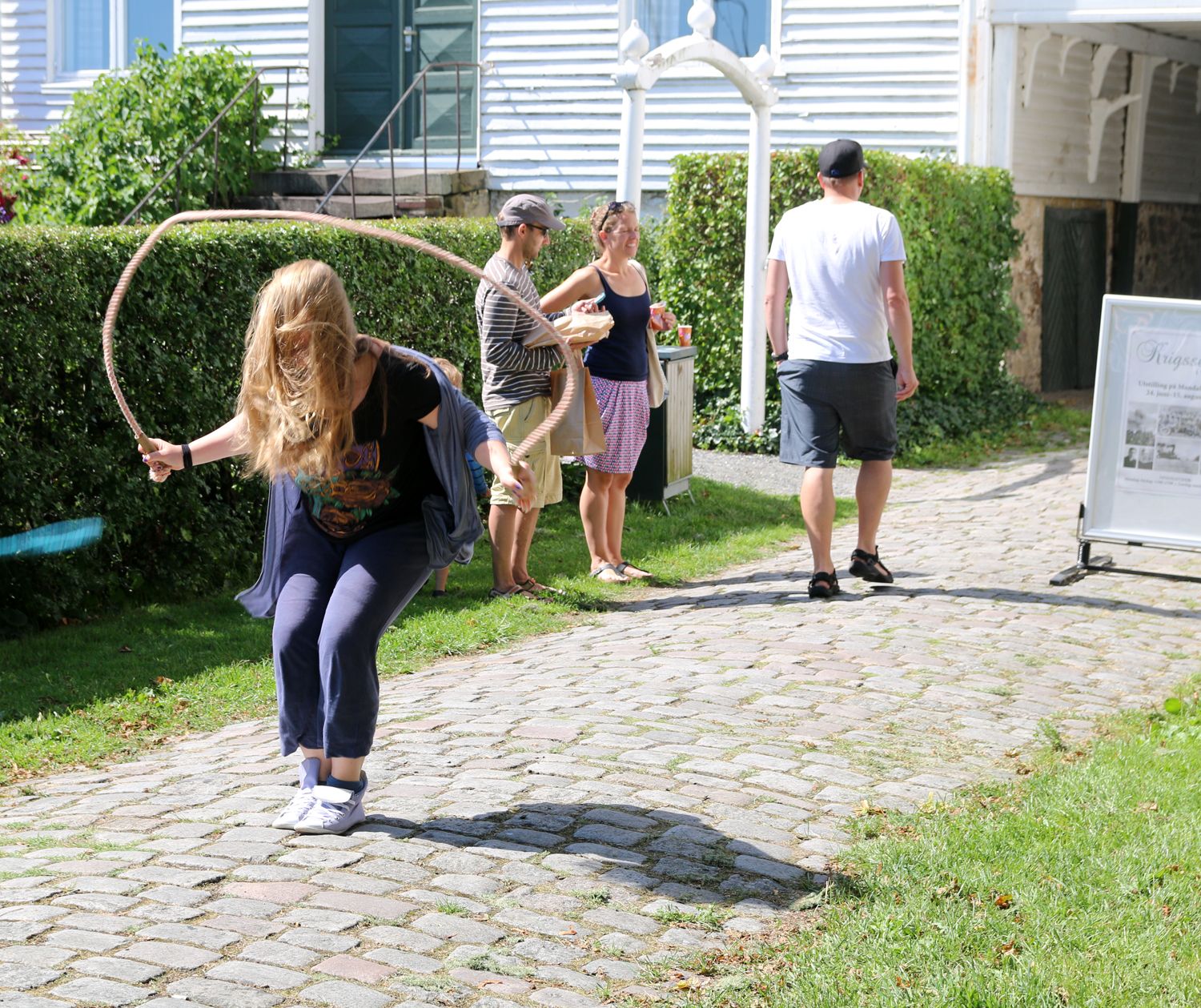 A girl skipping rope, with three others in the background looking at something else.