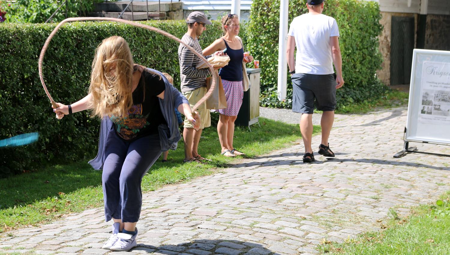 A girl skipping rope, with three others in the background looking at something else.