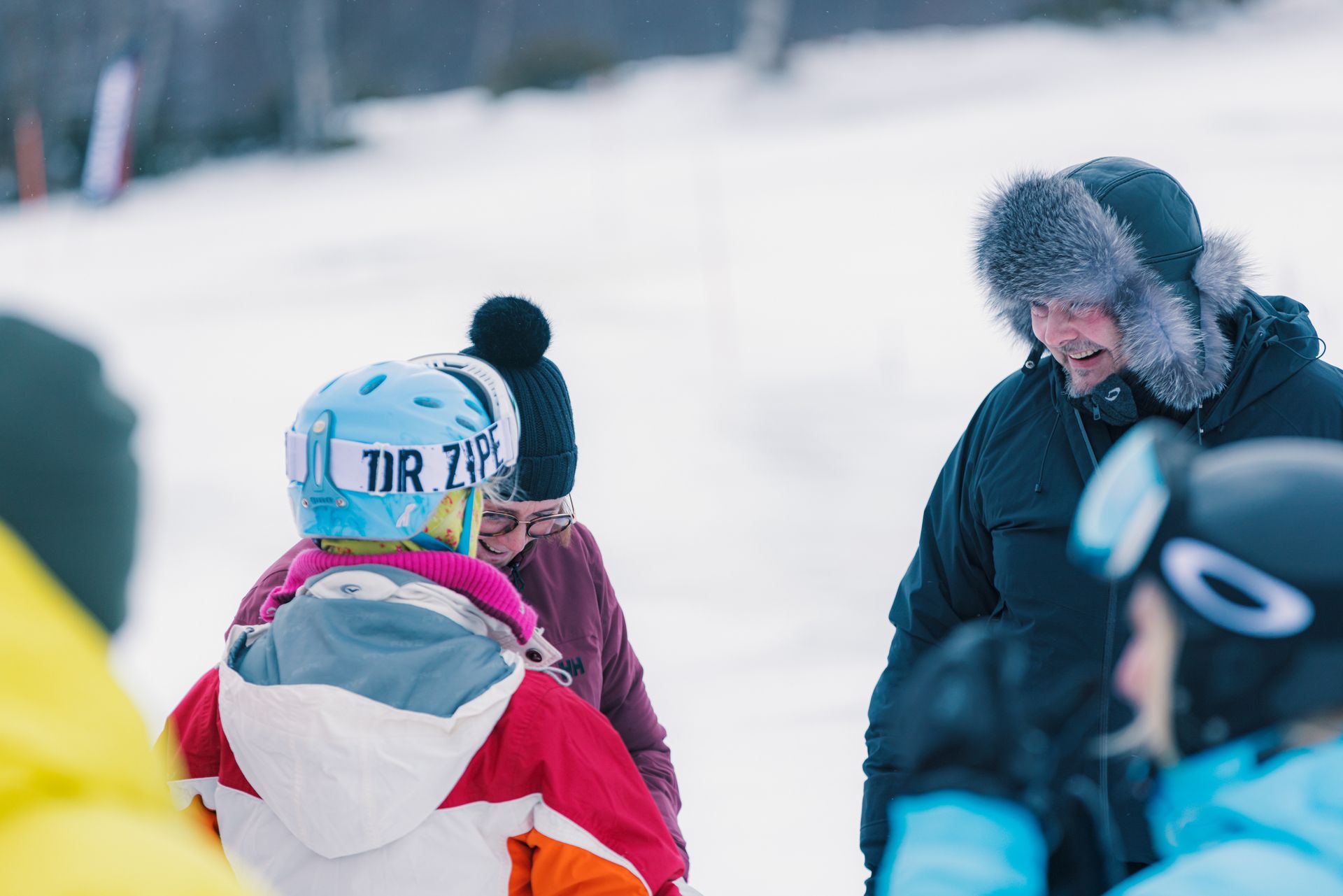 A group of people are chatting and enjoying themselves after a great snowmobile tour.