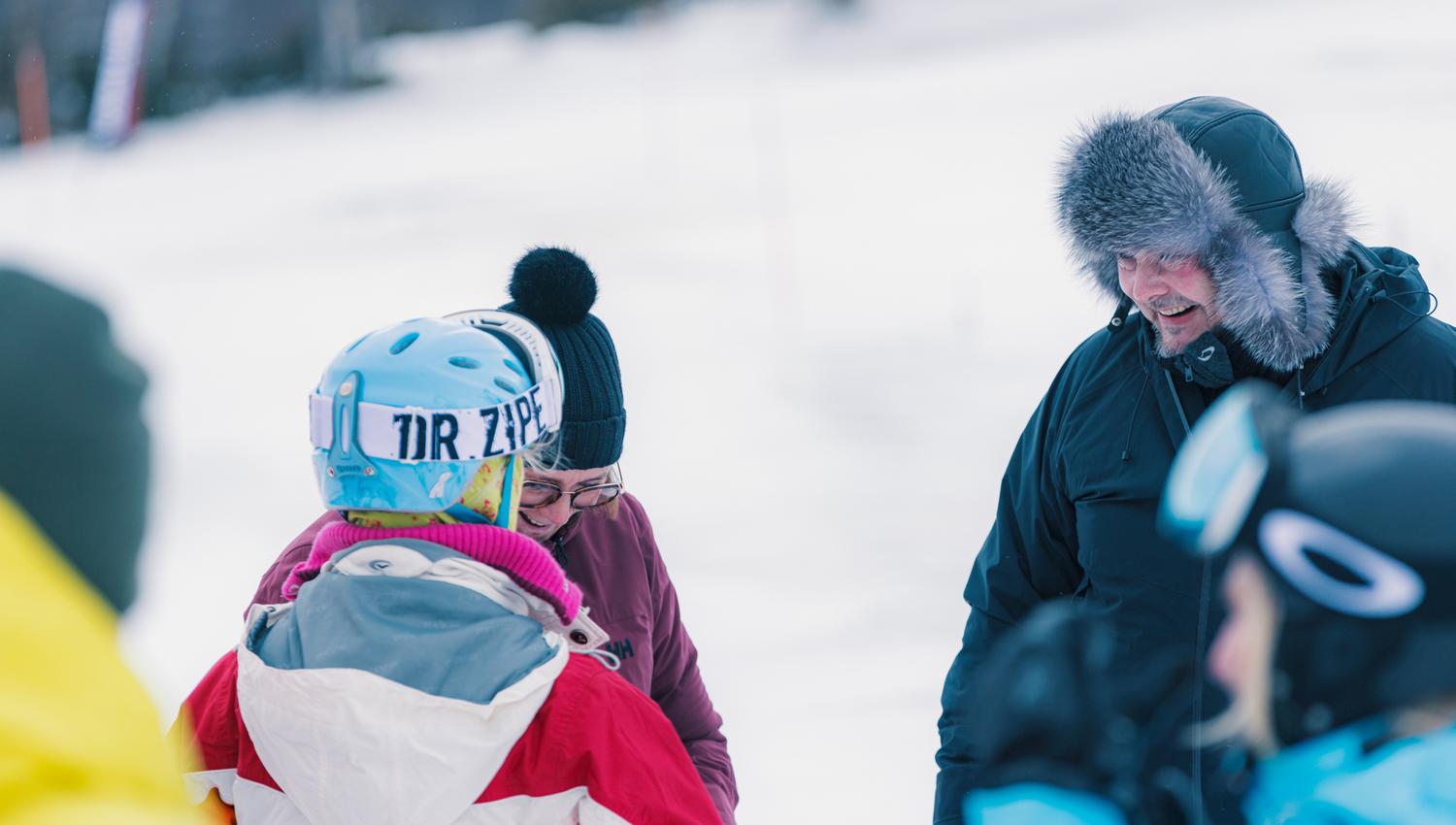 A group of people are chatting and enjoying themselves after a great snowmobile tour.