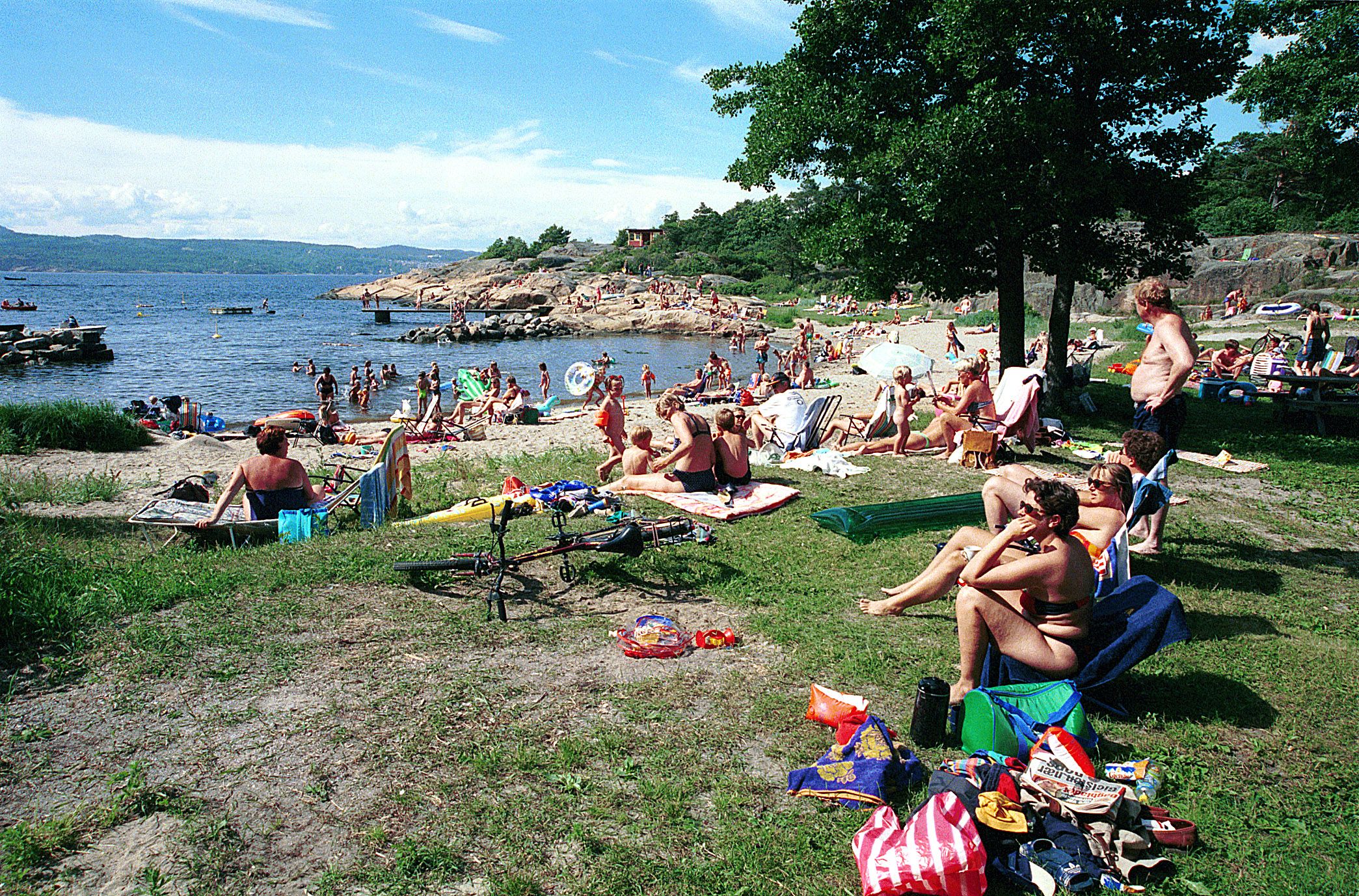 Mange mennesker på strand og gresslette