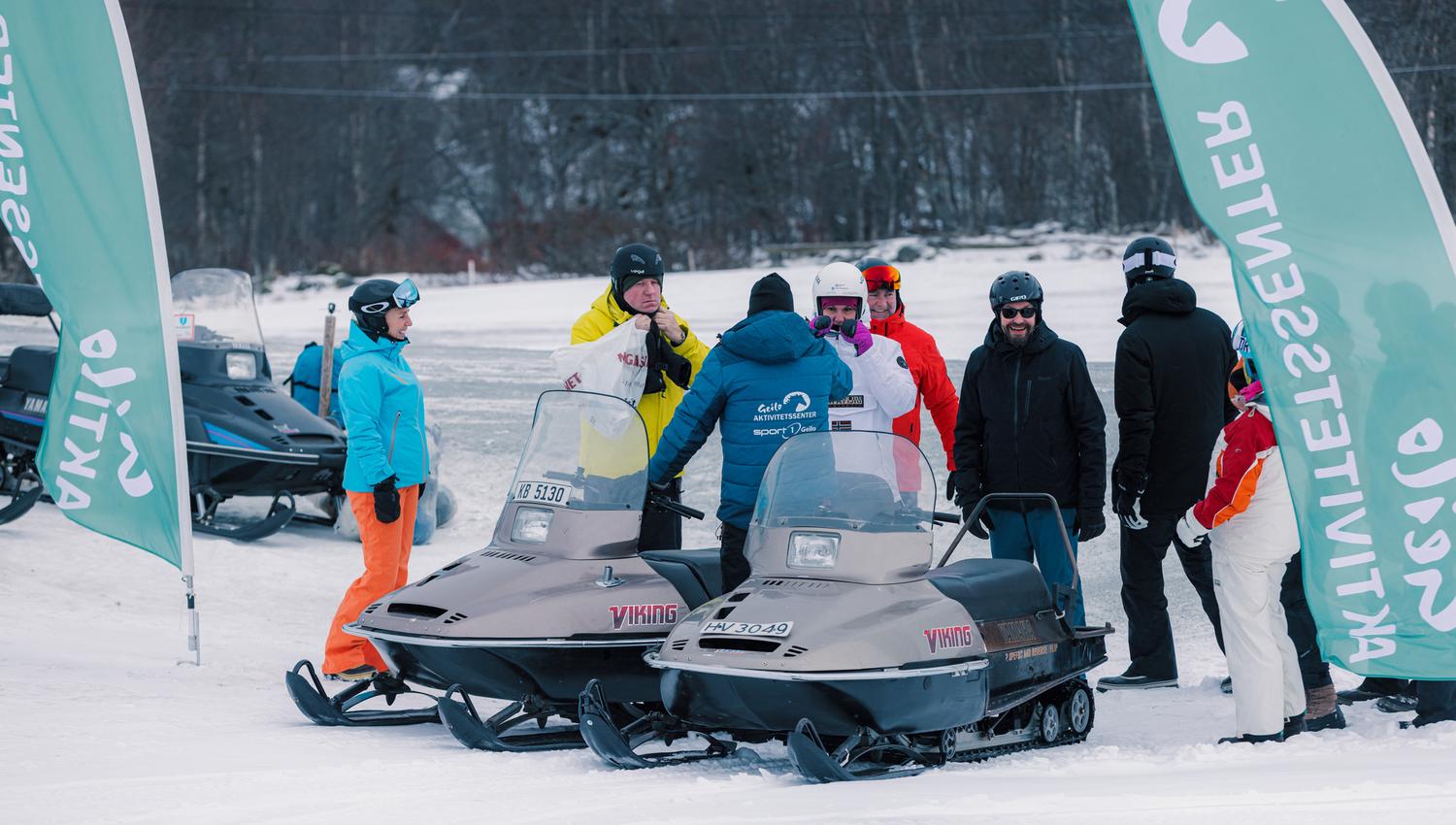A group of people are chatting and enjoying themselves after a great snowmobile tour.
