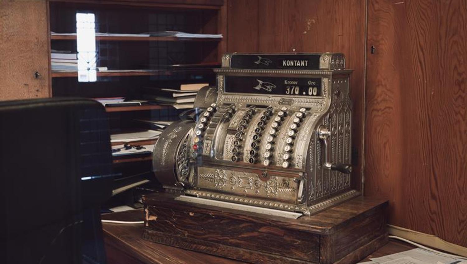 An old silver cash register with the word “Cash” displayed on the screen.