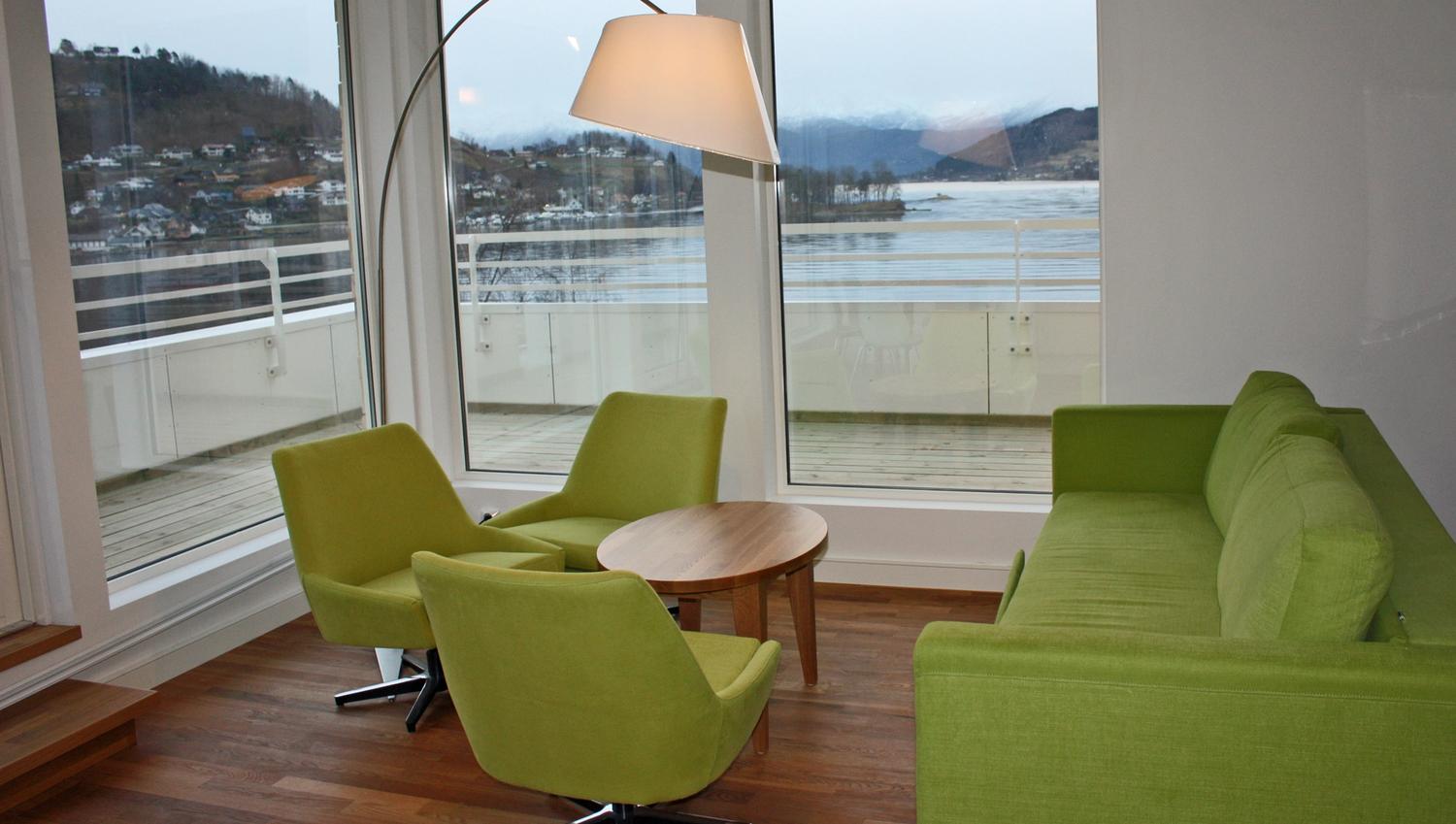 Modern lounge at Thon Hotel Sandven with stylish green furniture and a stunning view of the Hardangerfjord.