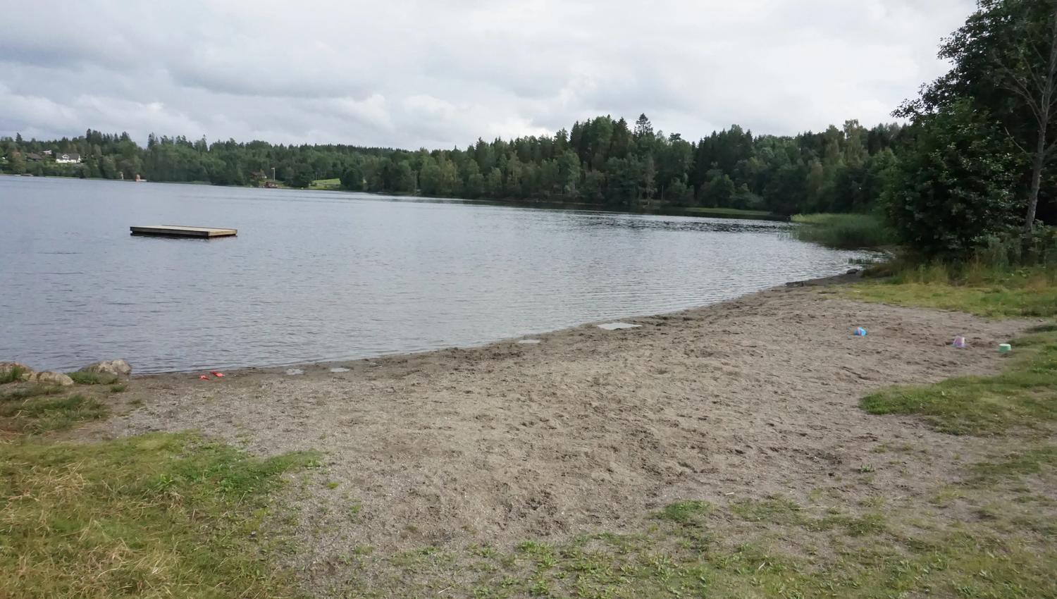 Sandstrand i skogen med badebrygge