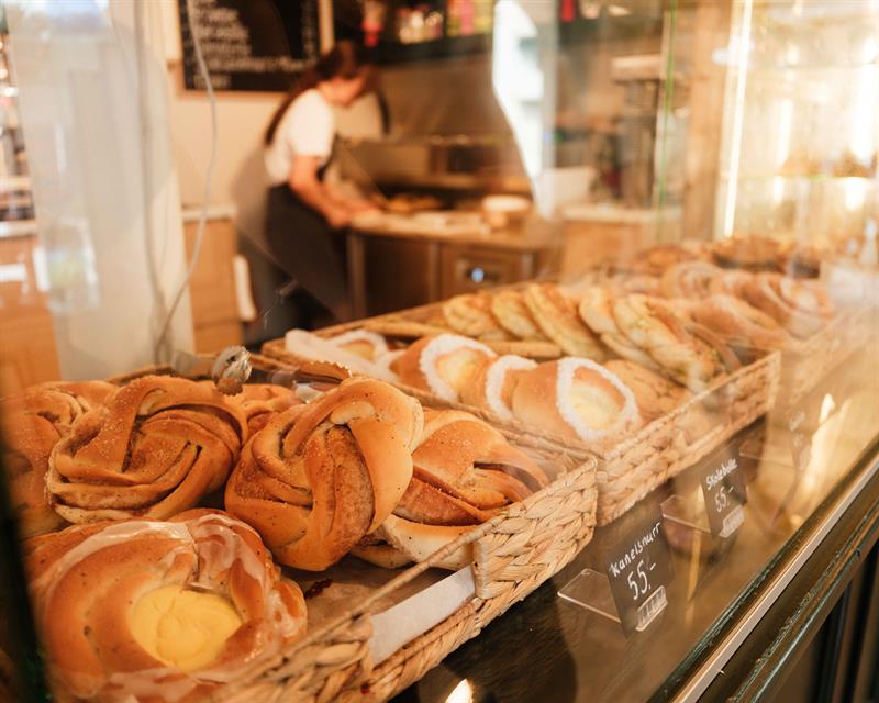 Yeast pastries and cinnamon buns are temptingly displayed in the counter at Iversen Bakery and Gallery, with the bakery and a staff member working in 