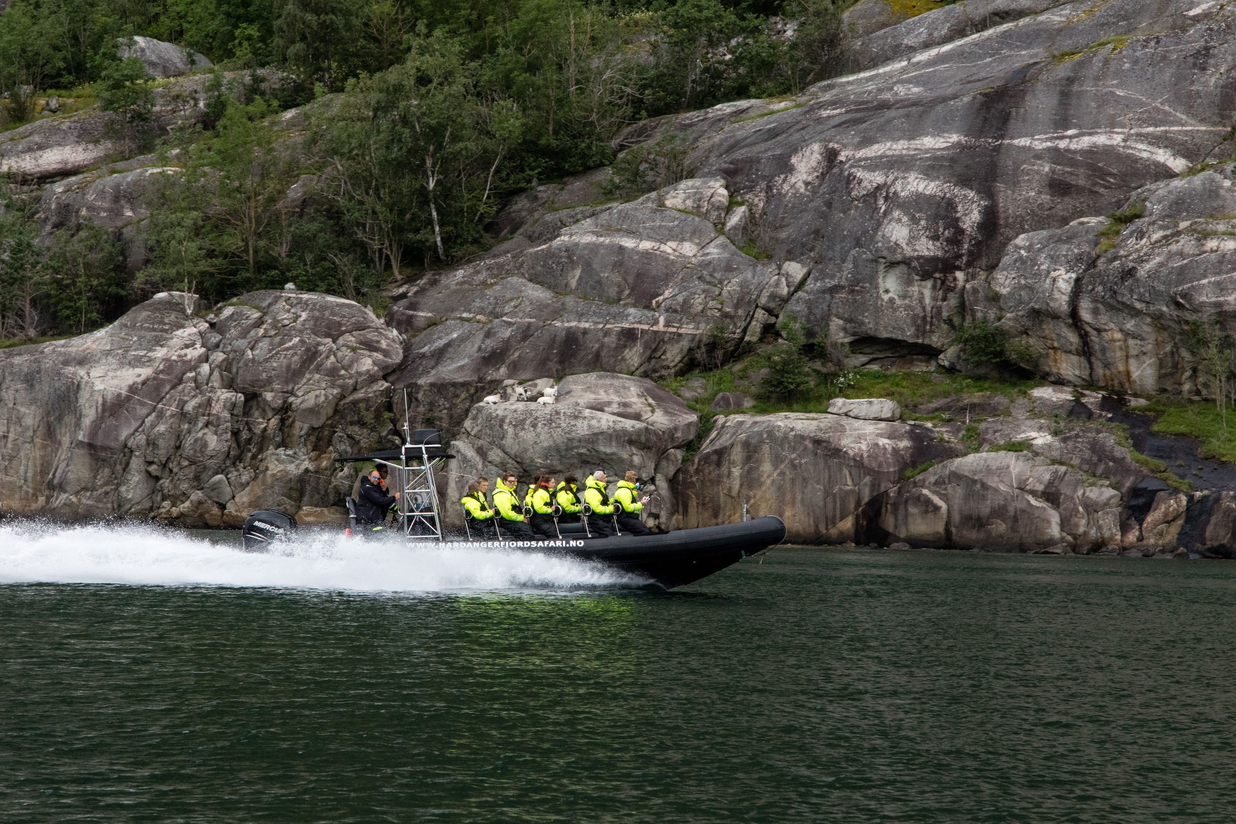 A rib boat filled with passengers speeding along the fjord.