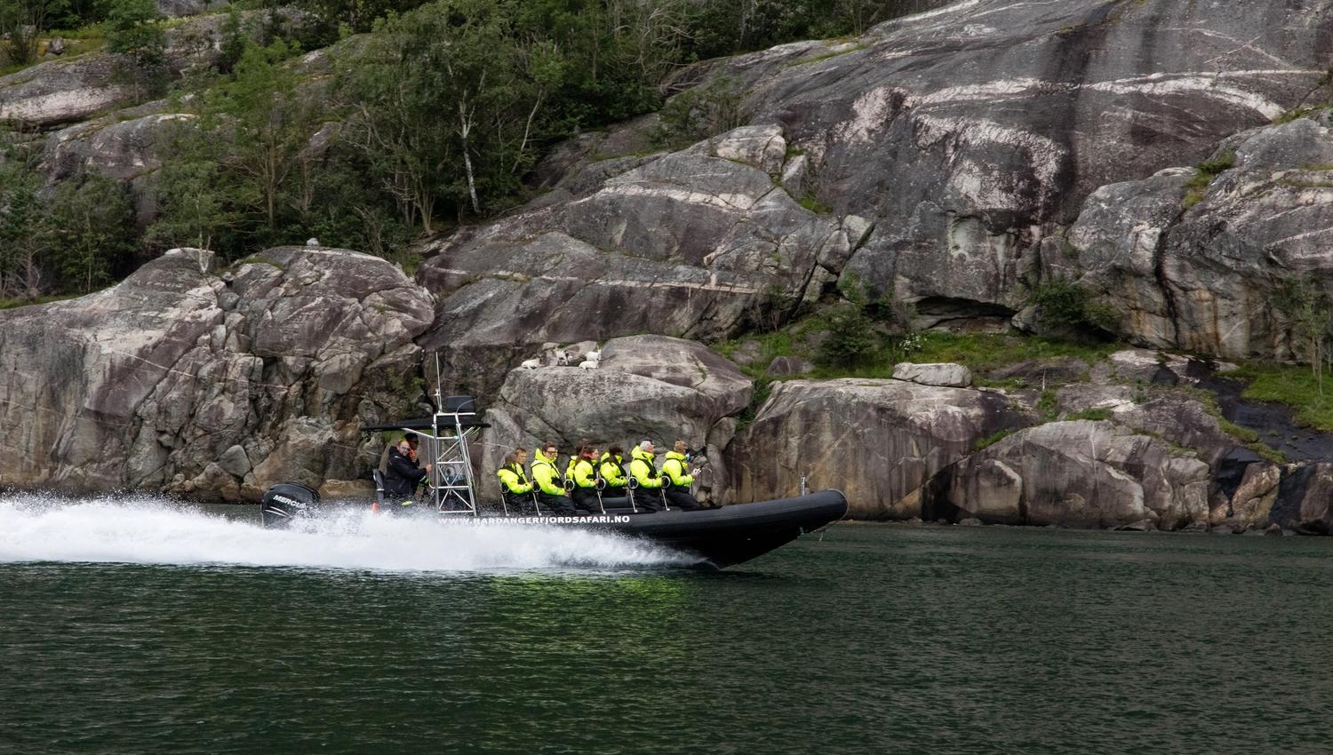 A rib boat filled with passengers speeding along the fjord.