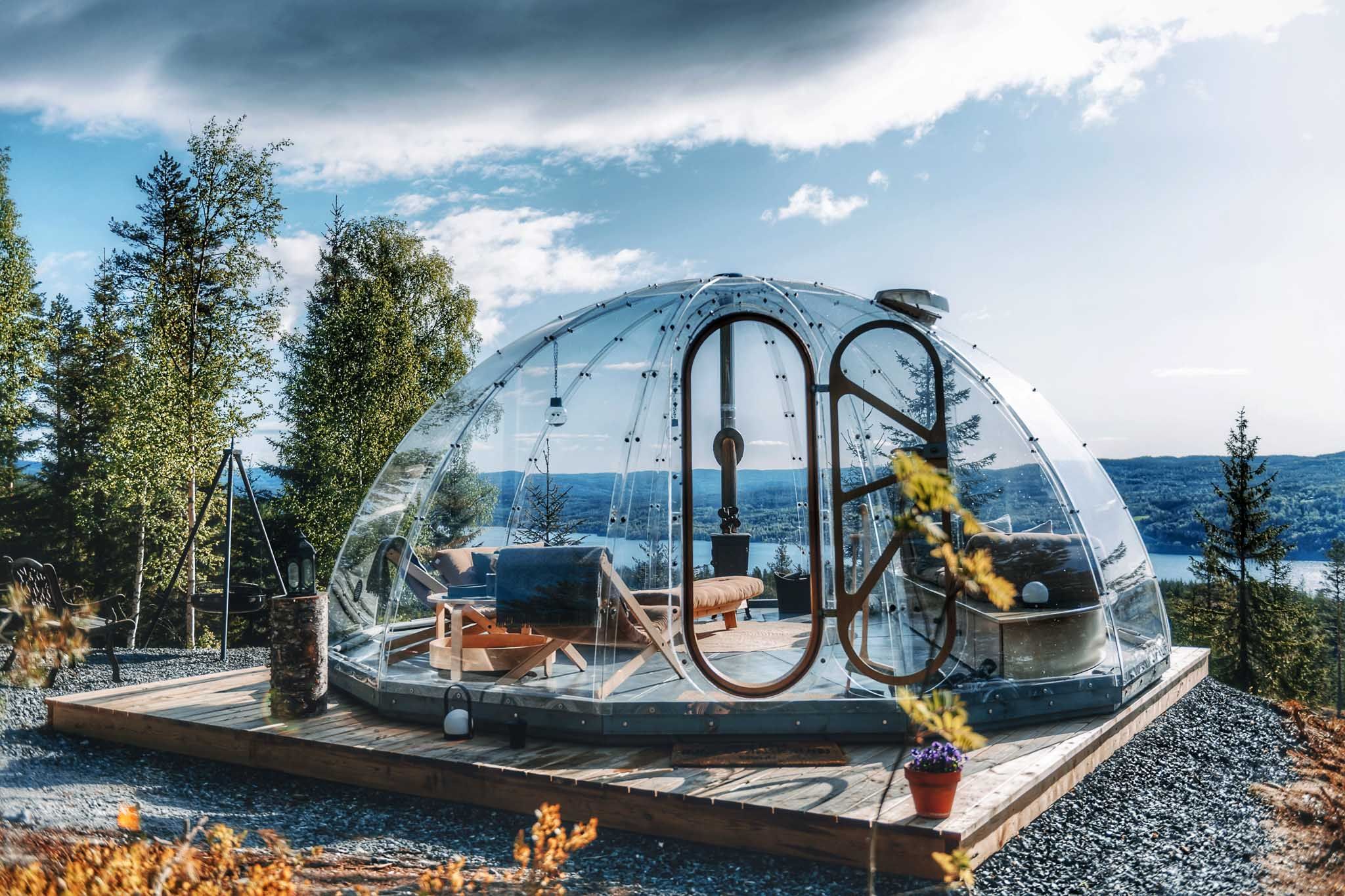 Glass igloo surrounded by trees overlooking the water