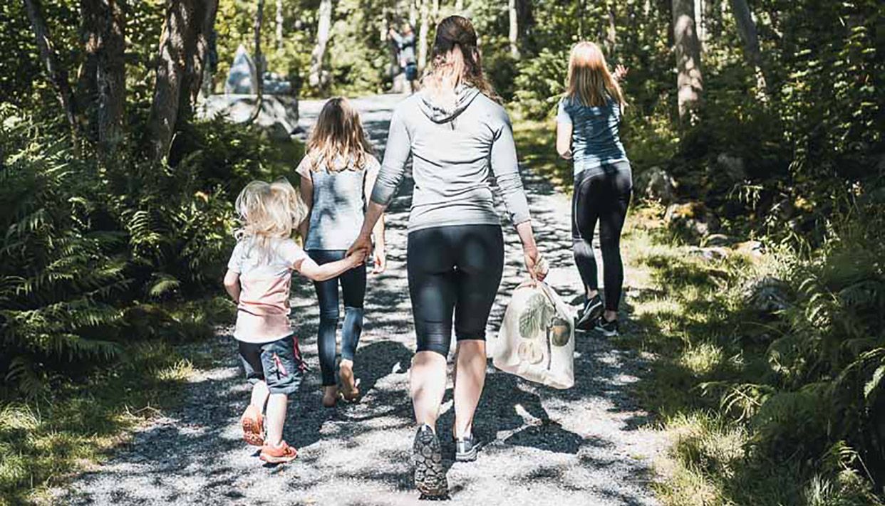 Family walking the forest trail in Steinparken Rosendal, surrounded by peaceful green nature.