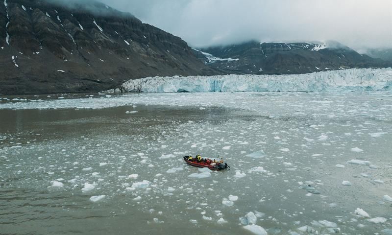 Åpen RIB ses i isfylt fjord. Brefront i bakgrunnen