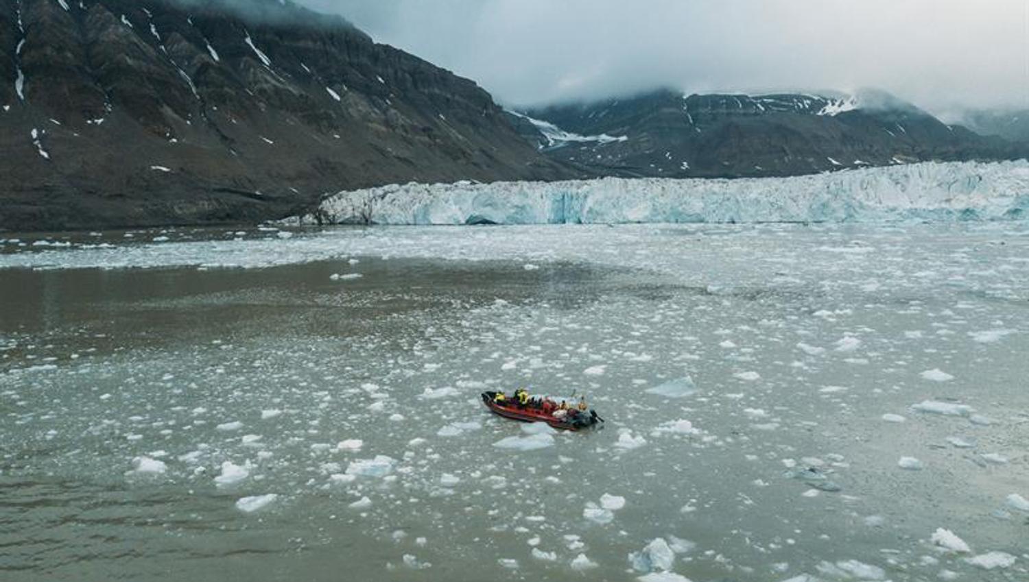 Åpen RIB ses i isfylt fjord. Brefront i bakgrunnen