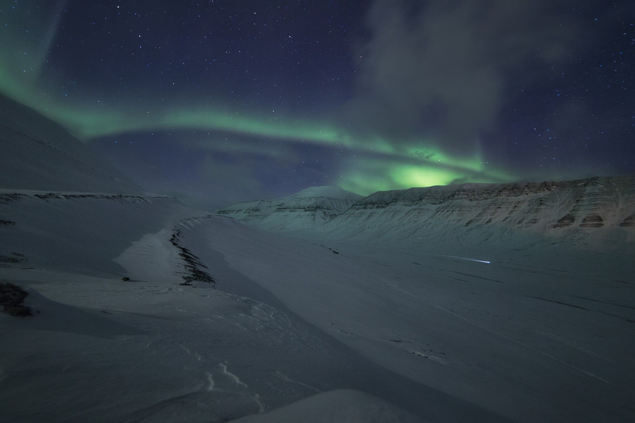 Snødekte fjell og dal, med nordlys himmelen over.