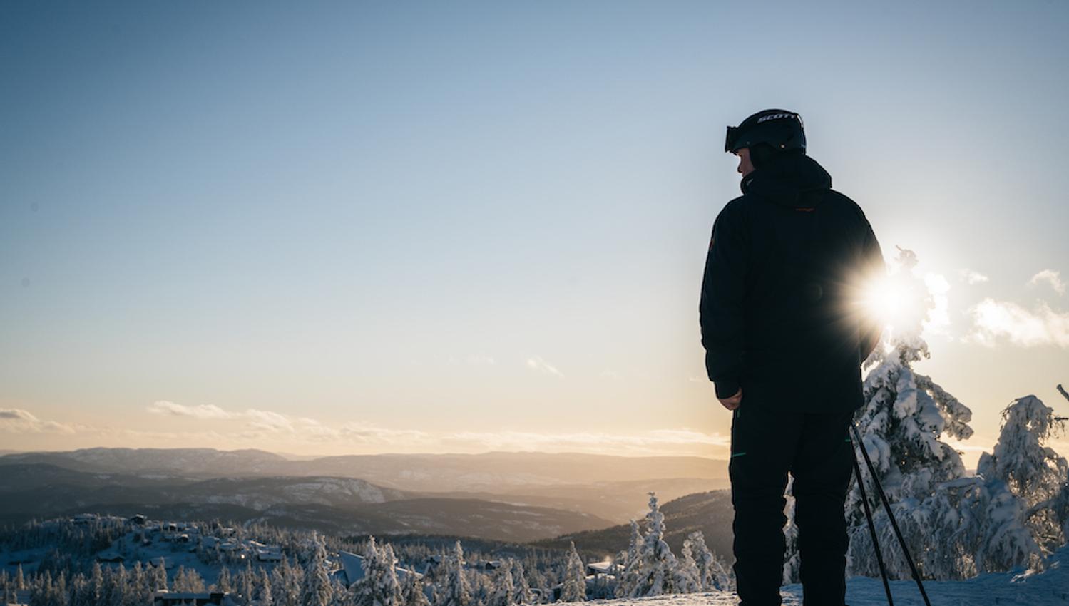 man on skis stands on a peak at Lifjell ski center and looks out over the landscape